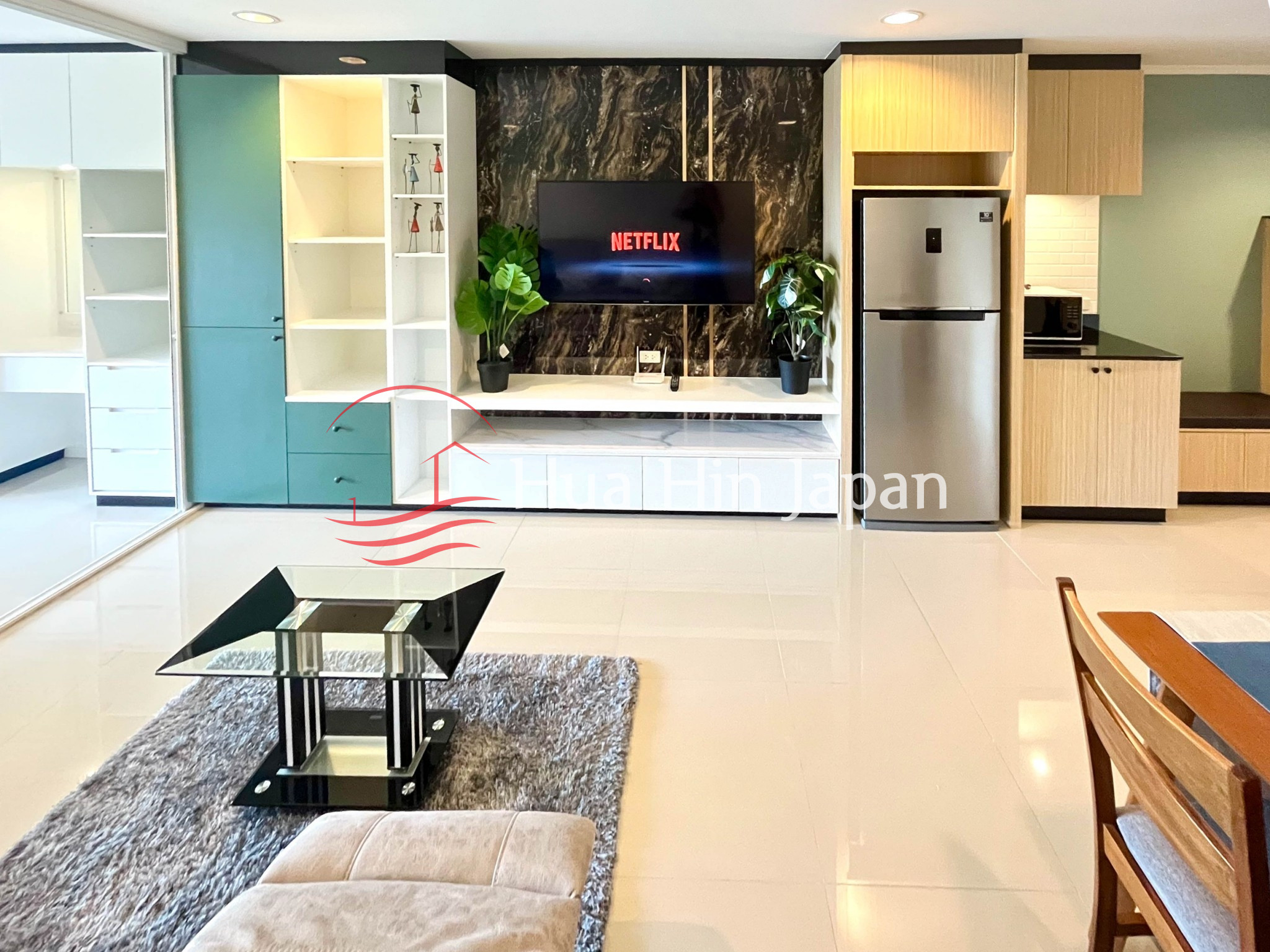 Modern living room with wall-mounted TV, built-in wooden storage, sofa, and large windows
