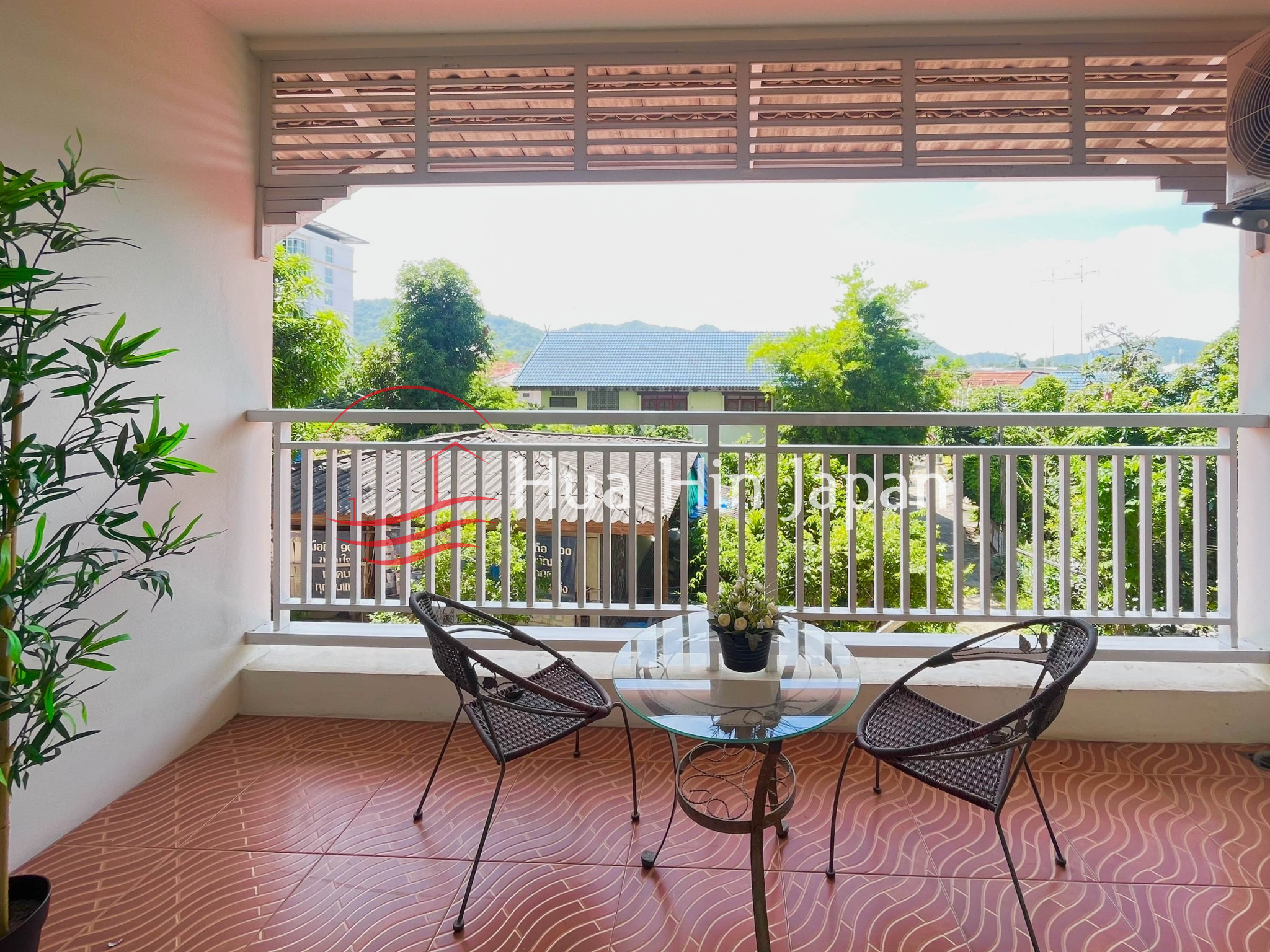 Apartment balcony with metal railing, outdoor view, trees, and neighboring buildings