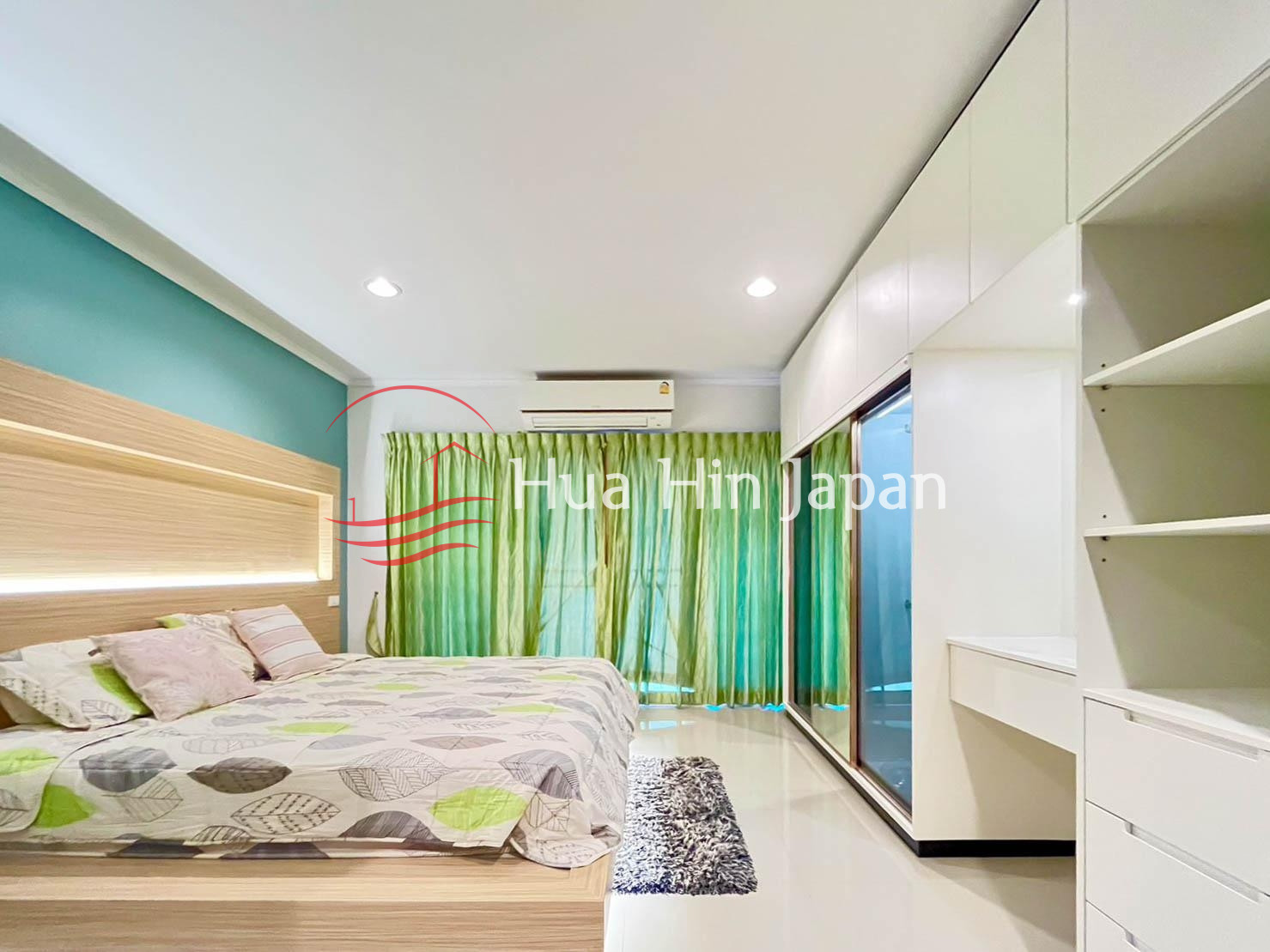 Bright modern bedroom with green walls, bed, wooden headboard, and built-in wardrobe