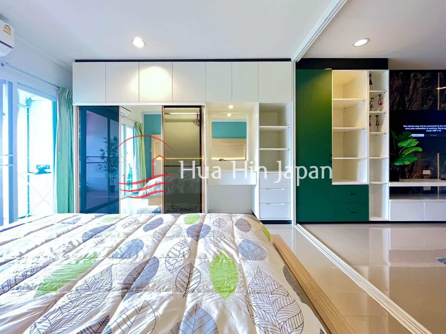 Modern bedroom interior with green accent wall, built-in wardrobe, and large windows