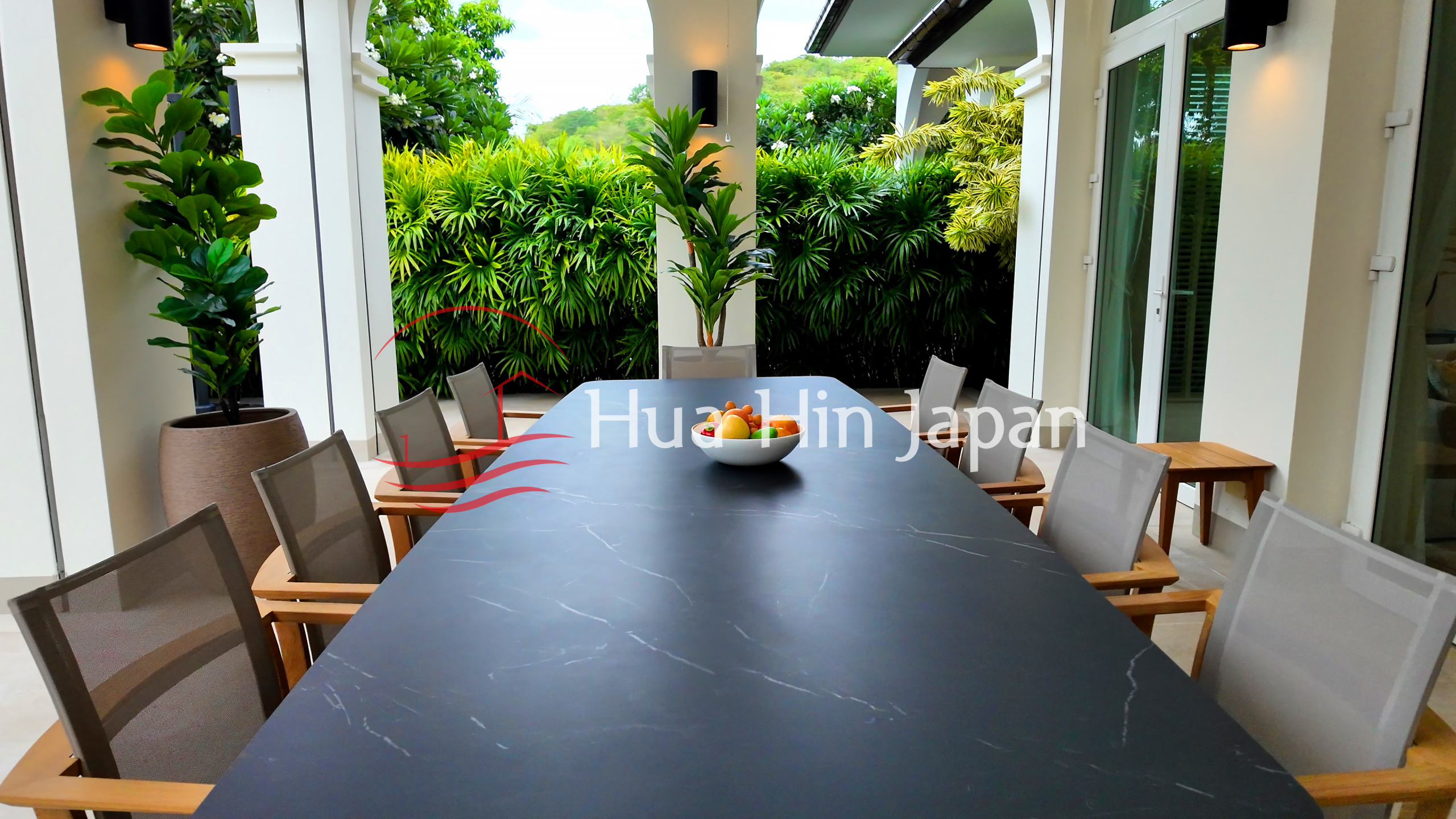 Elegant outdoor dining area with a large table, comfortable chairs, and lush tropical greenery