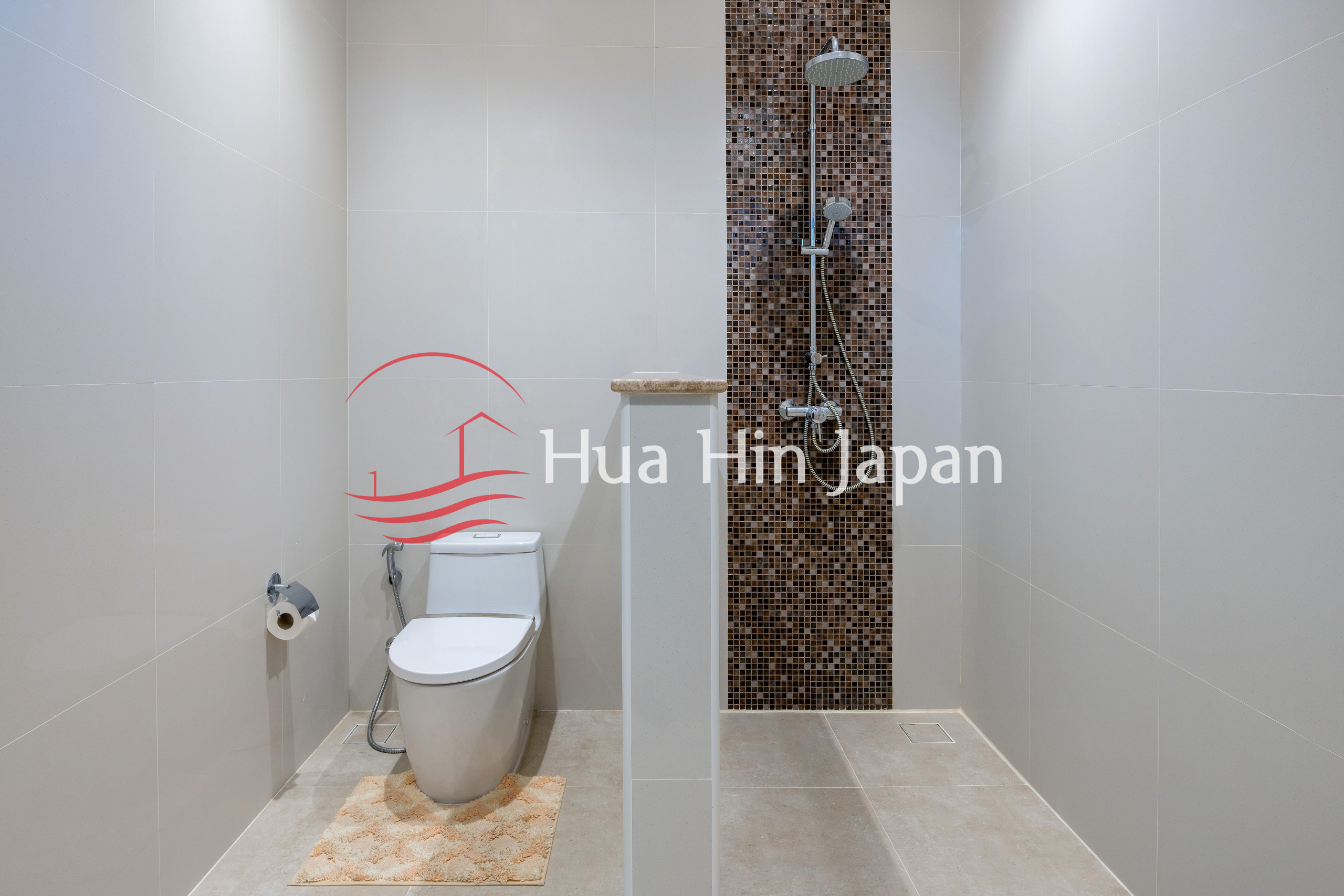 Modern tiled bathroom with a toilet and walk-in shower featuring a mosaic accent wall.