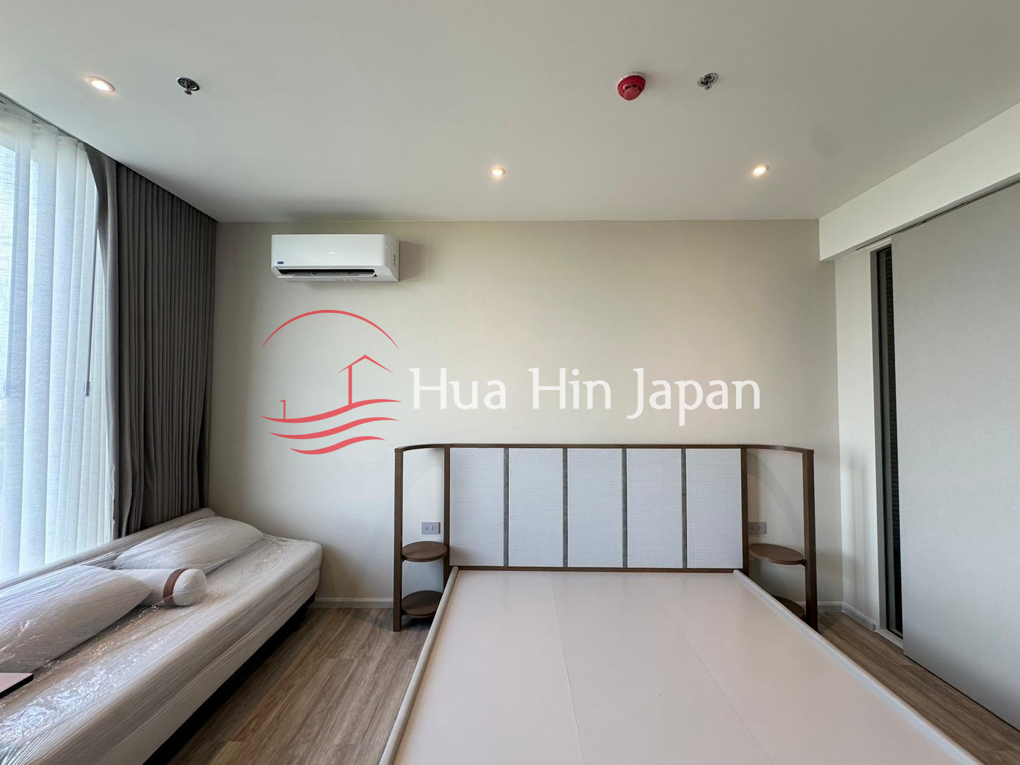 Modern bedroom with large bed, sofa, air conditioner, and floor-to-ceiling window