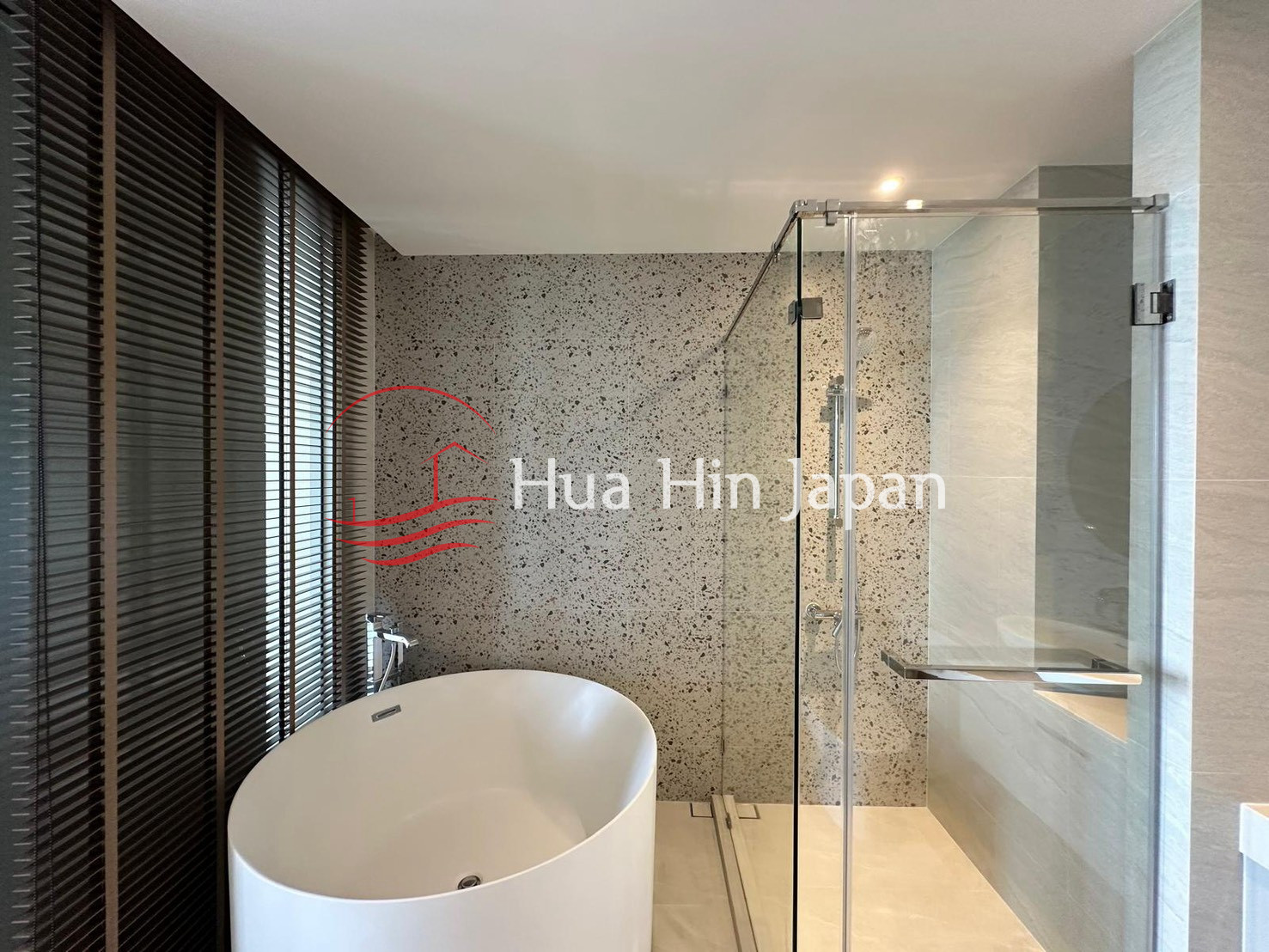 Modern bathroom with freestanding bathtub, glass shower enclosure, and textured tile walls