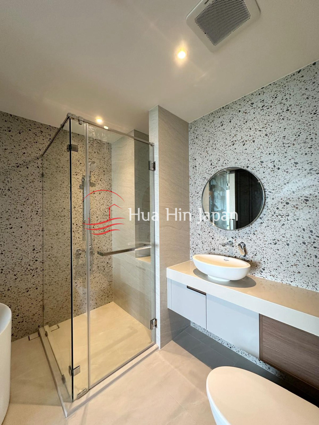 Modern bathroom with glass shower enclosure, round mirror, floating vanity, and vessel sink