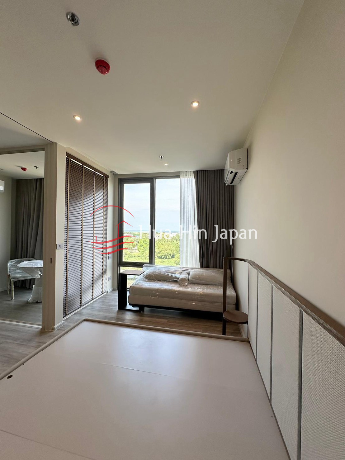 Modern bedroom with sofa, large windows, wardrobe, and air conditioning
