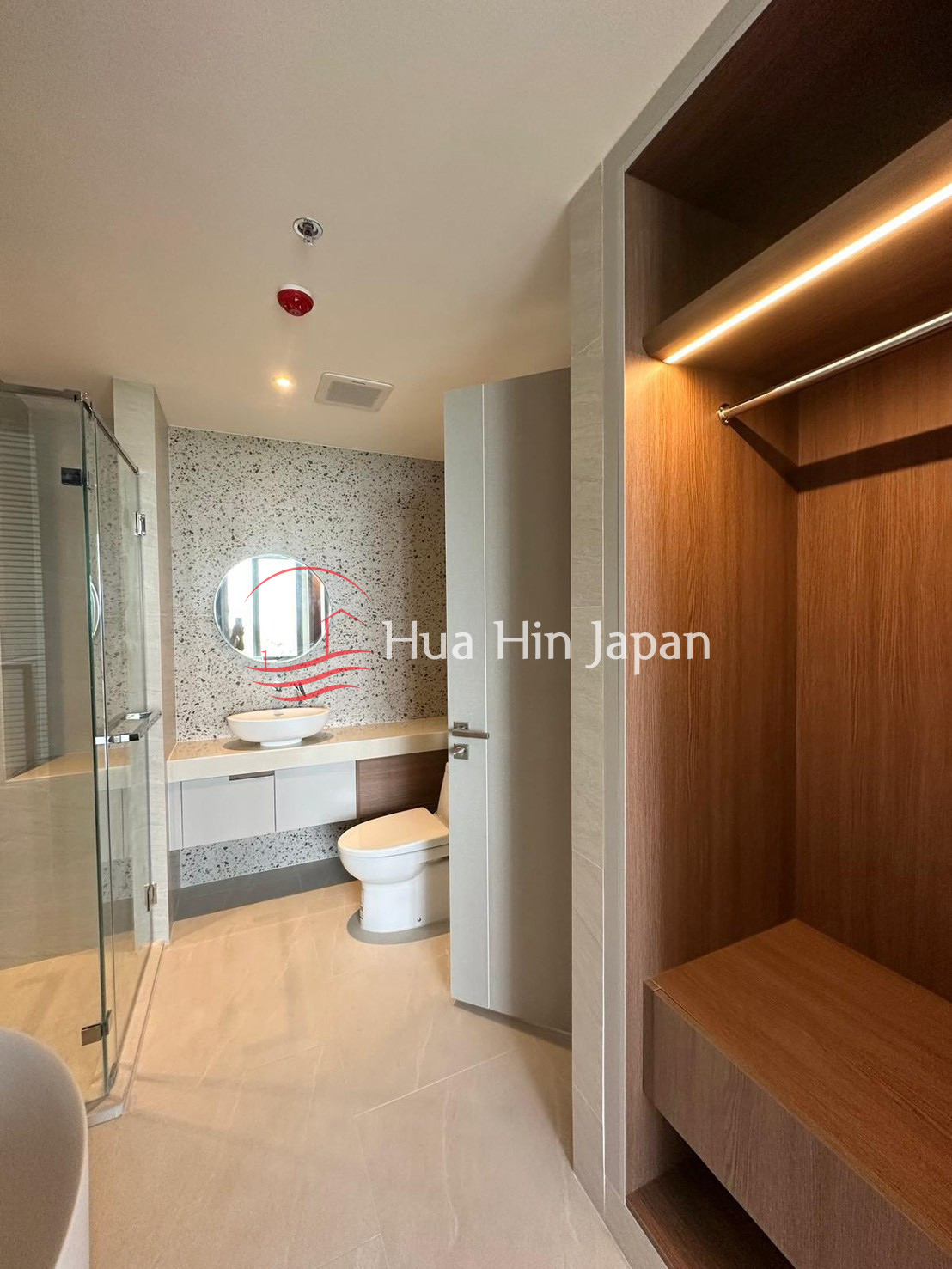 Modern bathroom with glass shower, vanity, toilet, and built-in wooden wardrobe