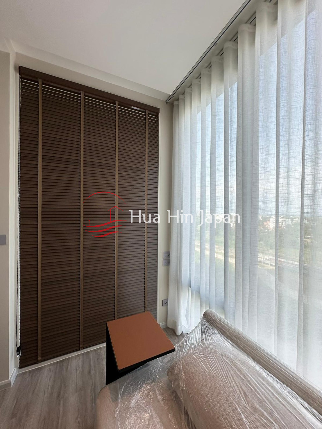 Bright window seating area with sheer curtains, wooden blinds, and small side table
