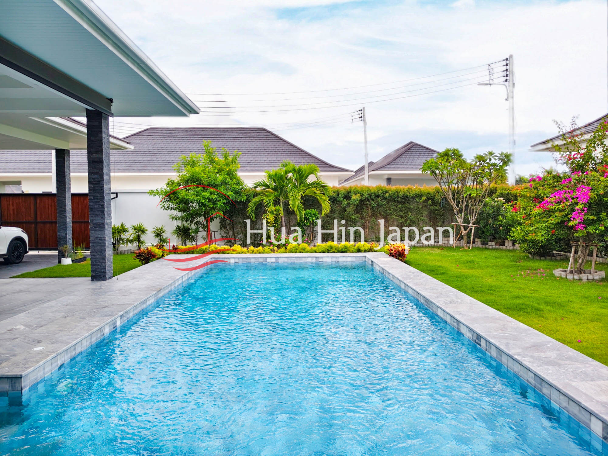 Large rectangular swimming pool beside a modern villa with landscaped garden
