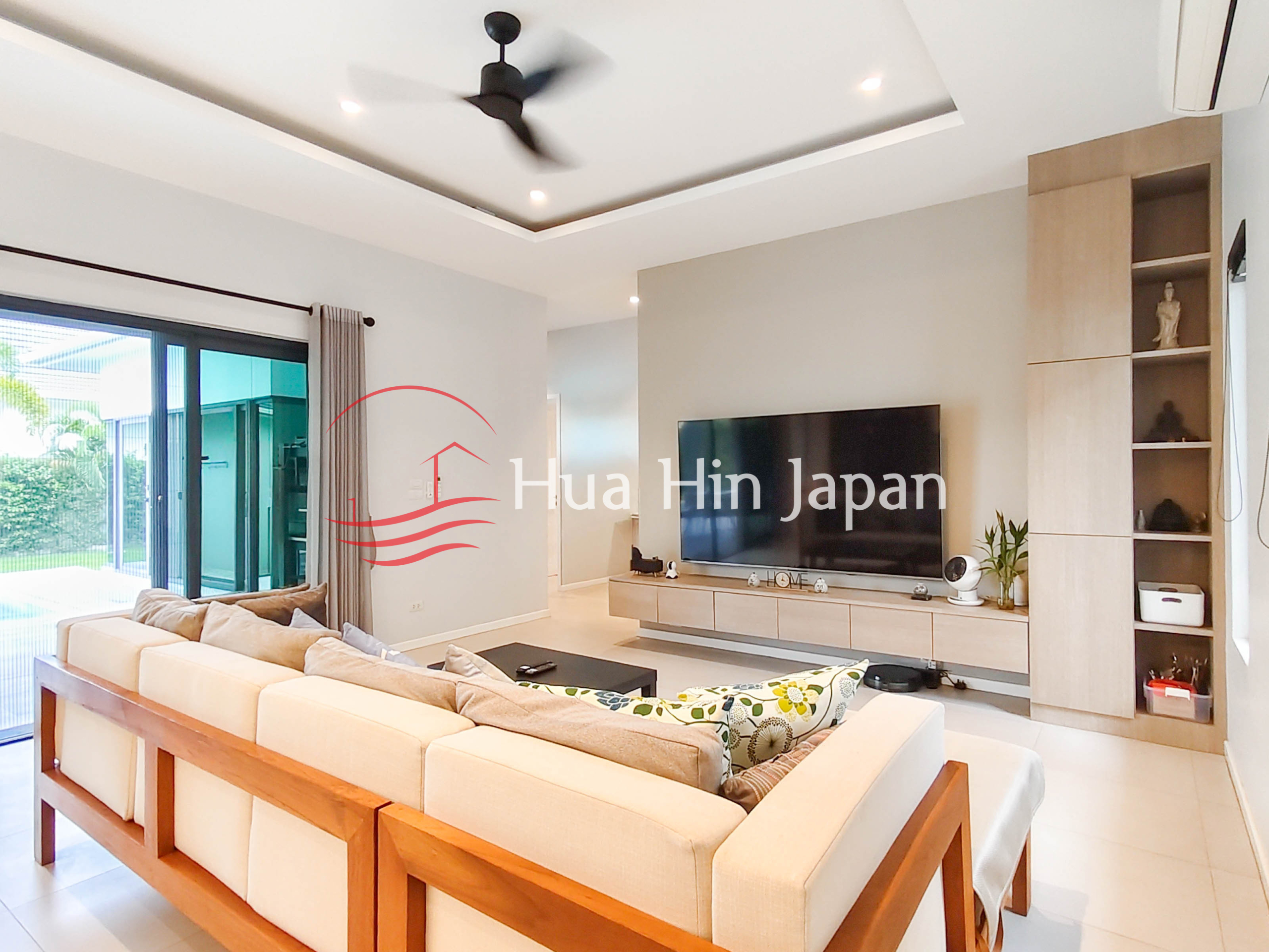 Modern living room with large sectional sofa, wall-mounted TV, built-in shelving and sliding glass doors
