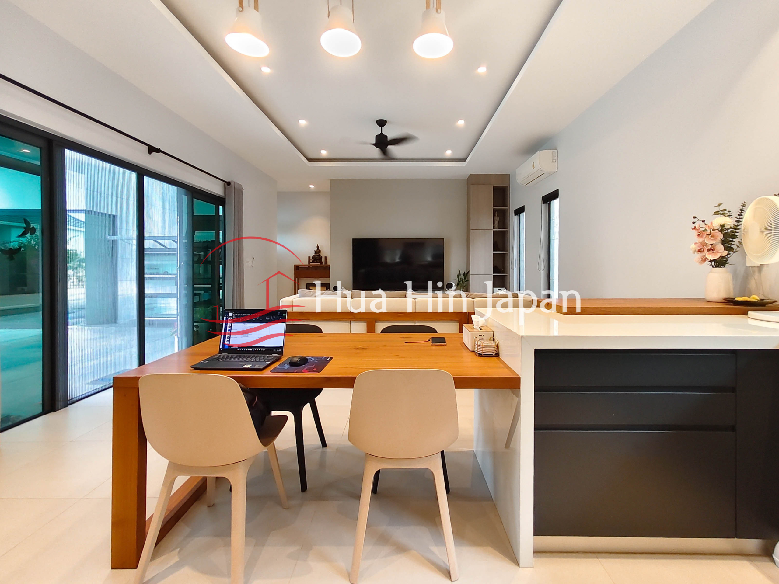 Modern open-plan living and dining area with wooden dining table, kitchen island and television
