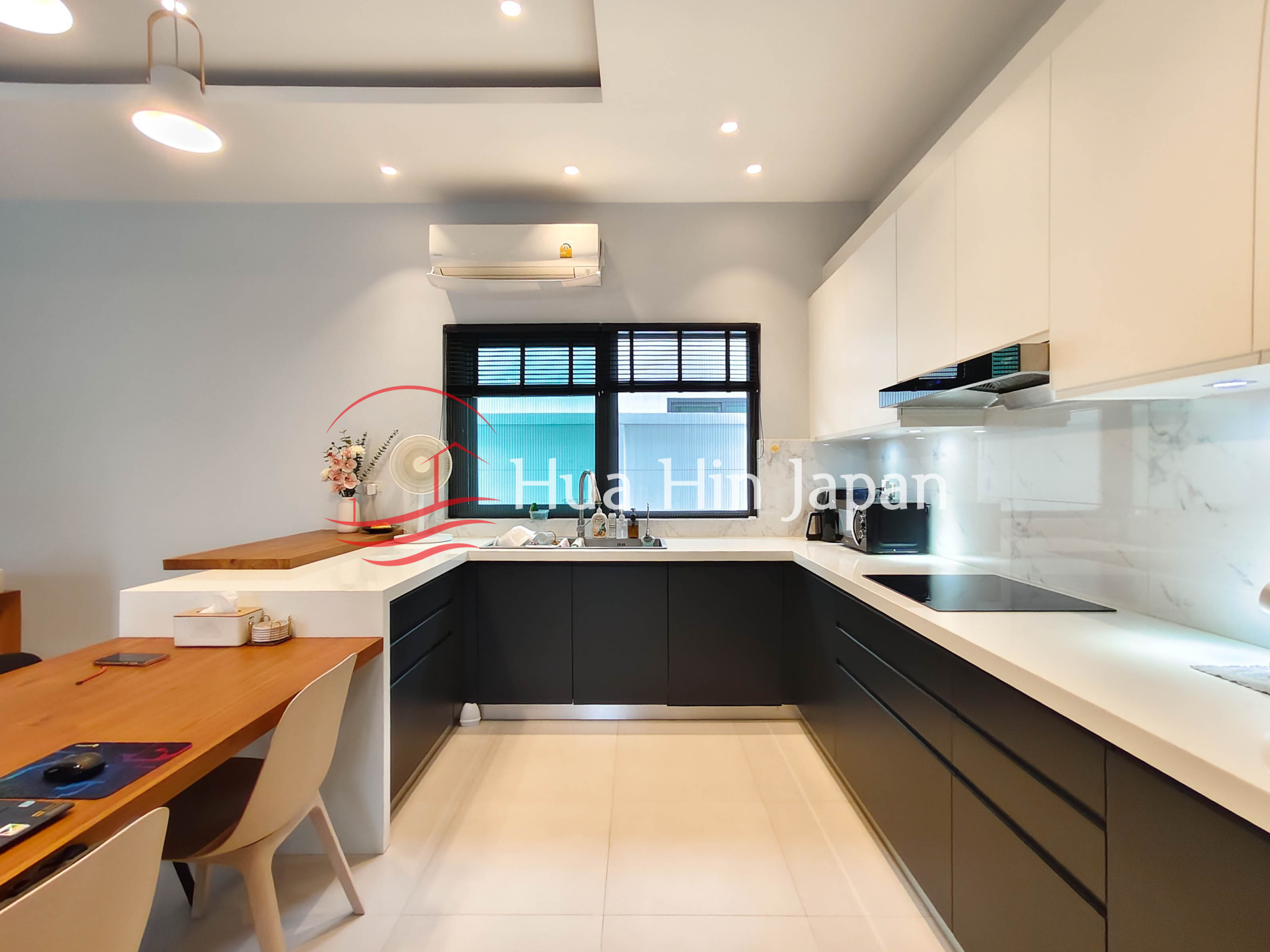 Modern U-shaped kitchen with black lower cabinets, white upper cabinets, marble backsplash and dining table