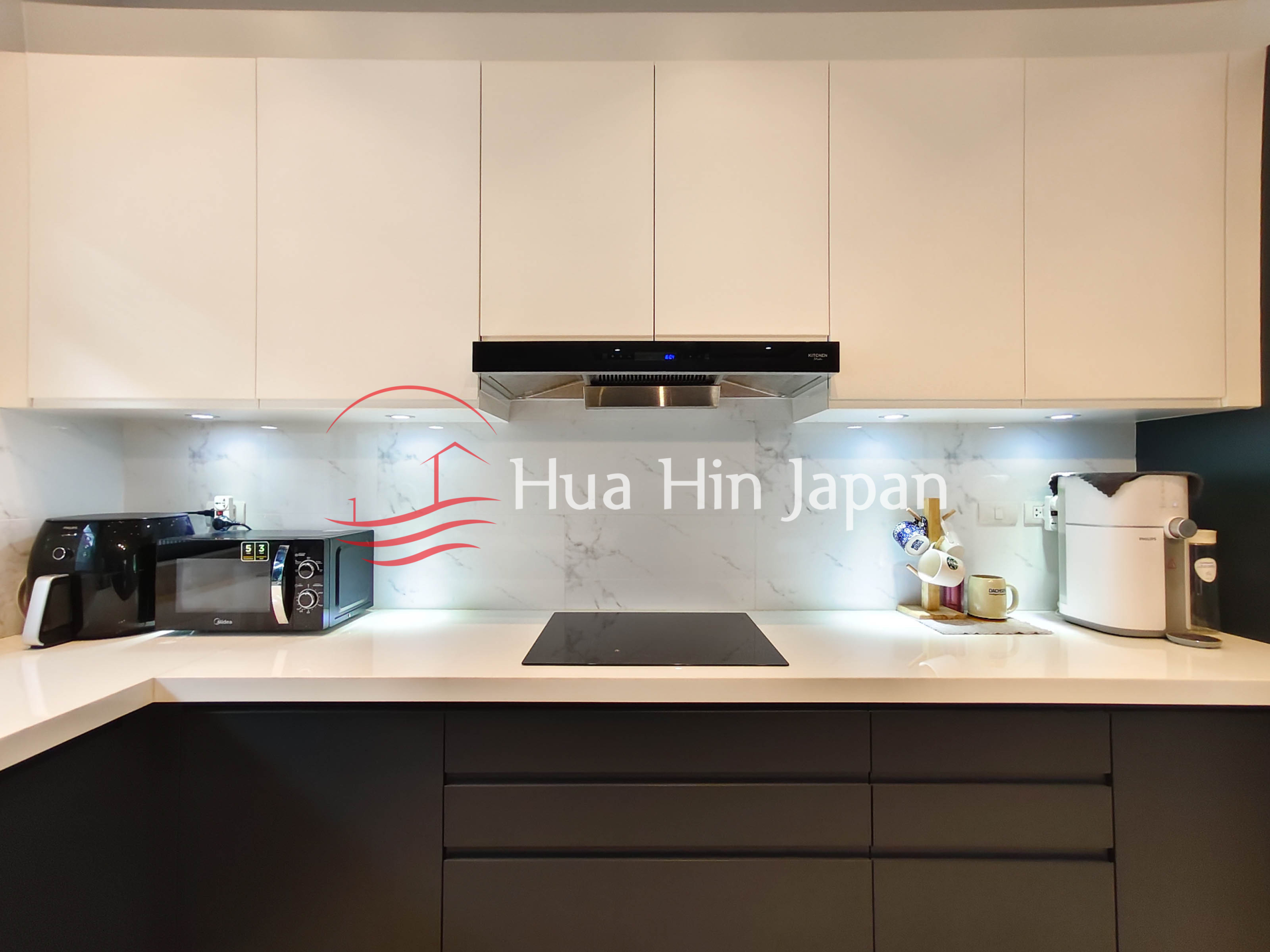 Modern kitchen with white cabinets, black lower cabinets, induction cooktop and countertop appliances
