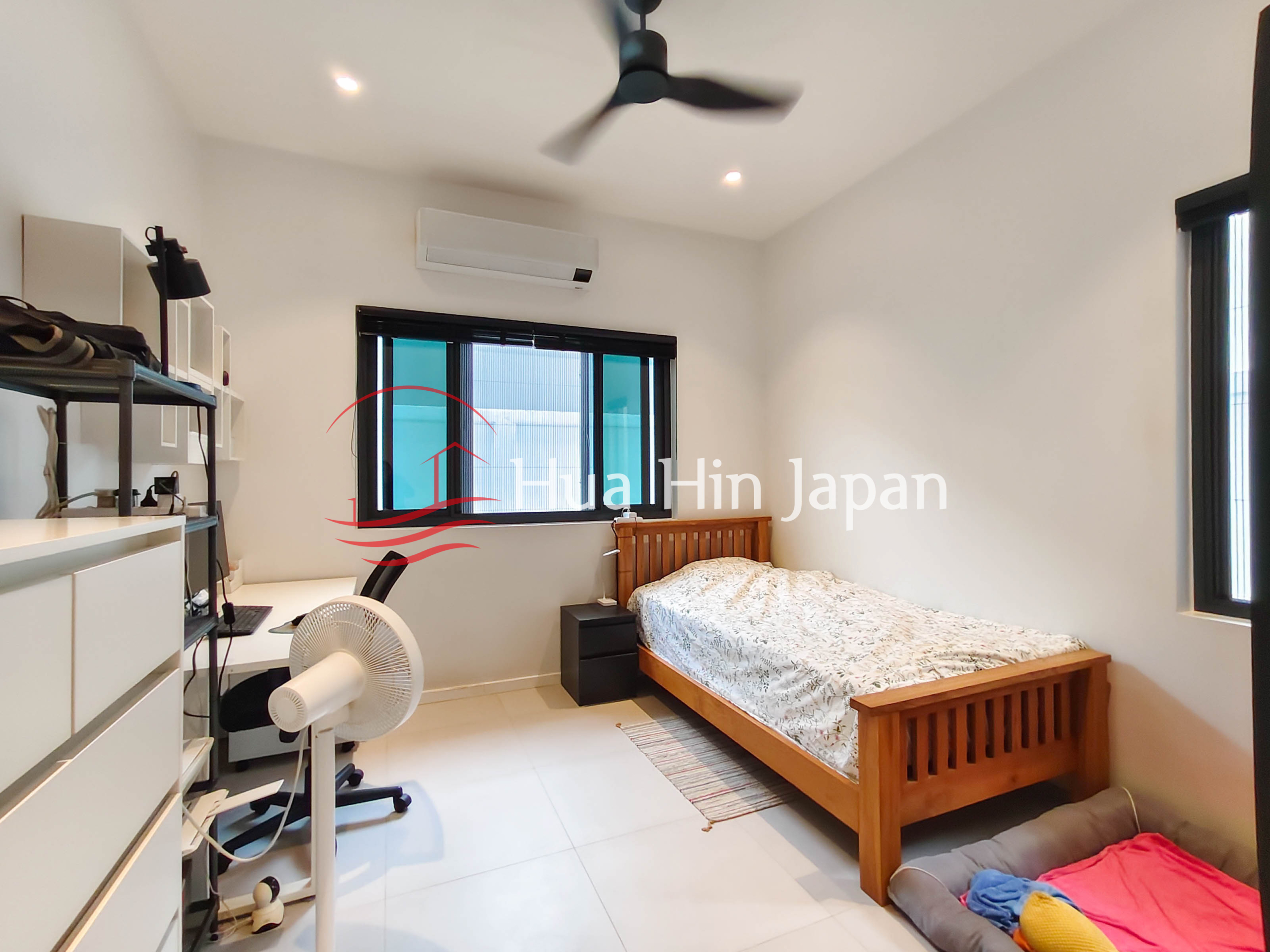 Bright bedroom with wooden single bed, desk, ceiling fan and air conditioner