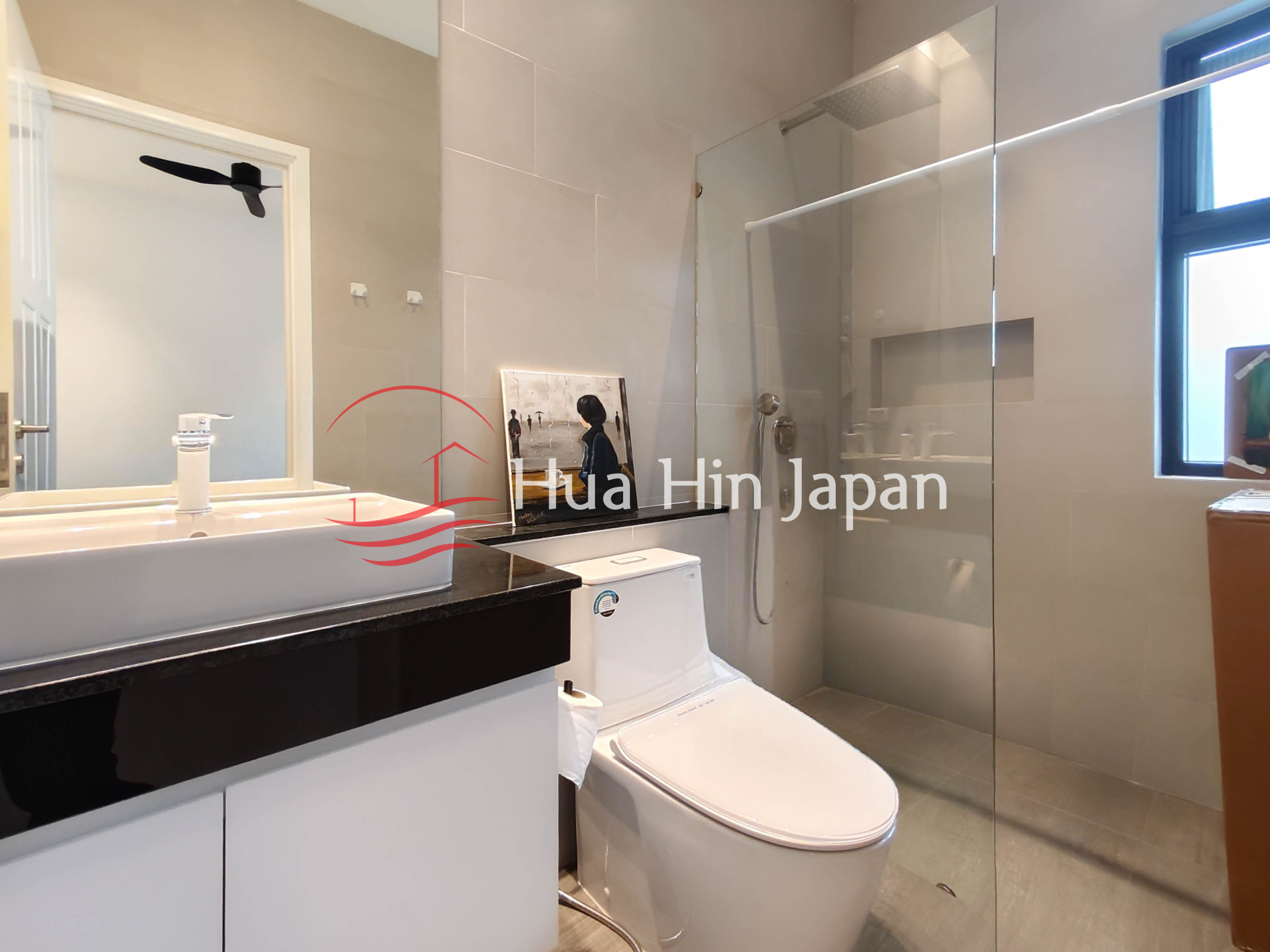 Modern bathroom with glass-enclosed shower, white toilet, vanity and large mirror