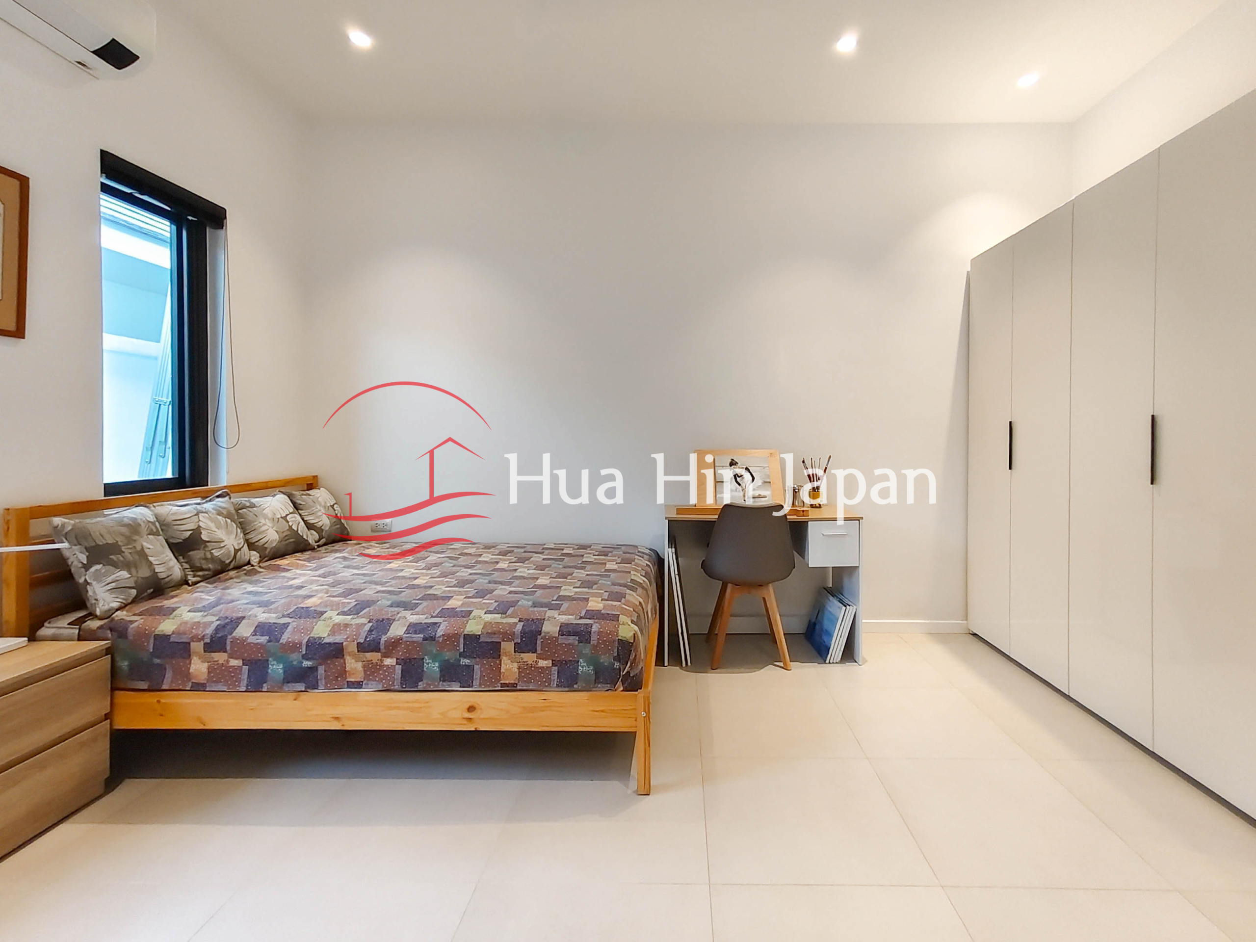 Modern bedroom with wooden bed, desk and large wardrobe