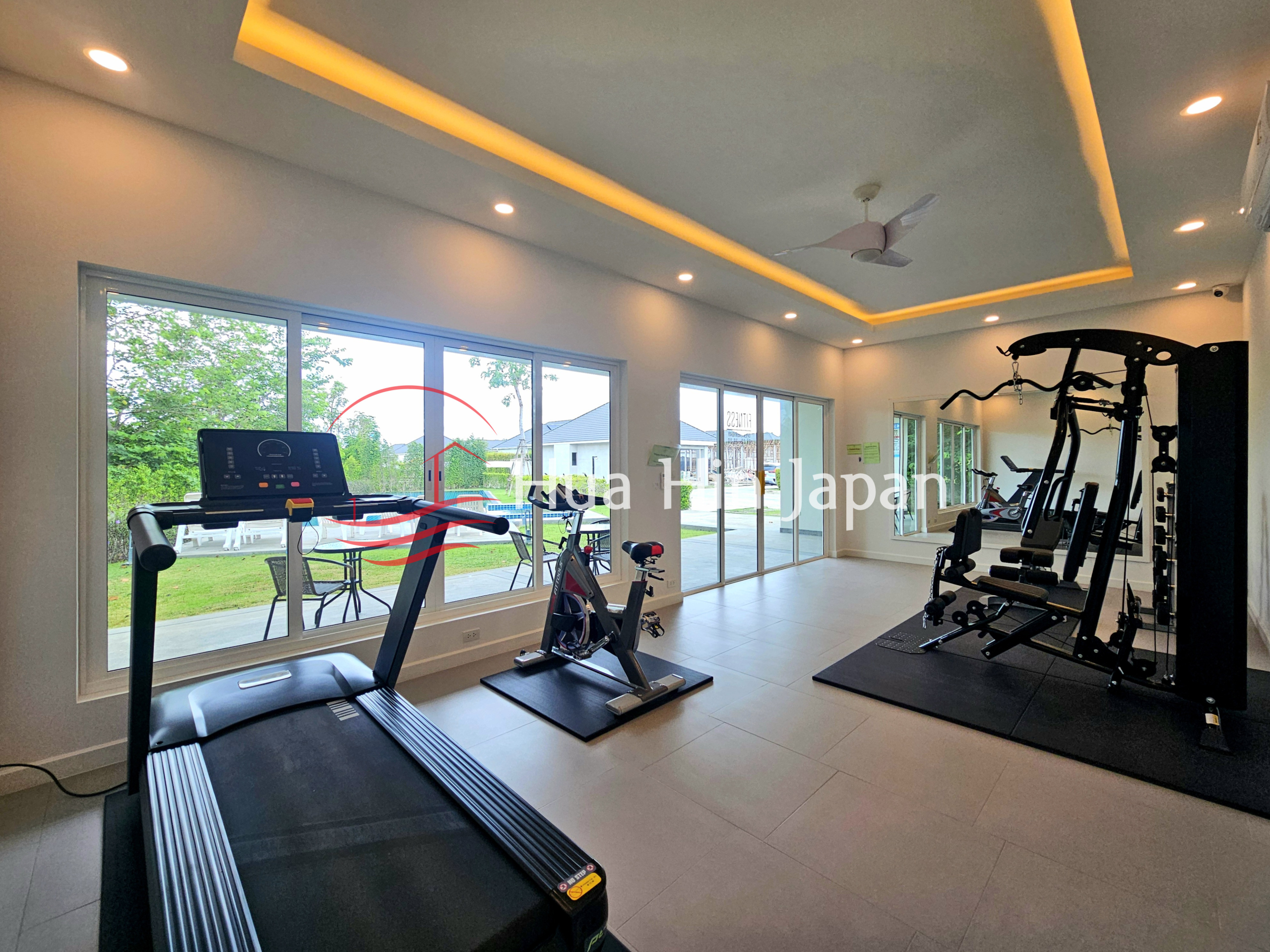 Modern private home gym with treadmill, exercise bike, multi-function weight machine, and large windows