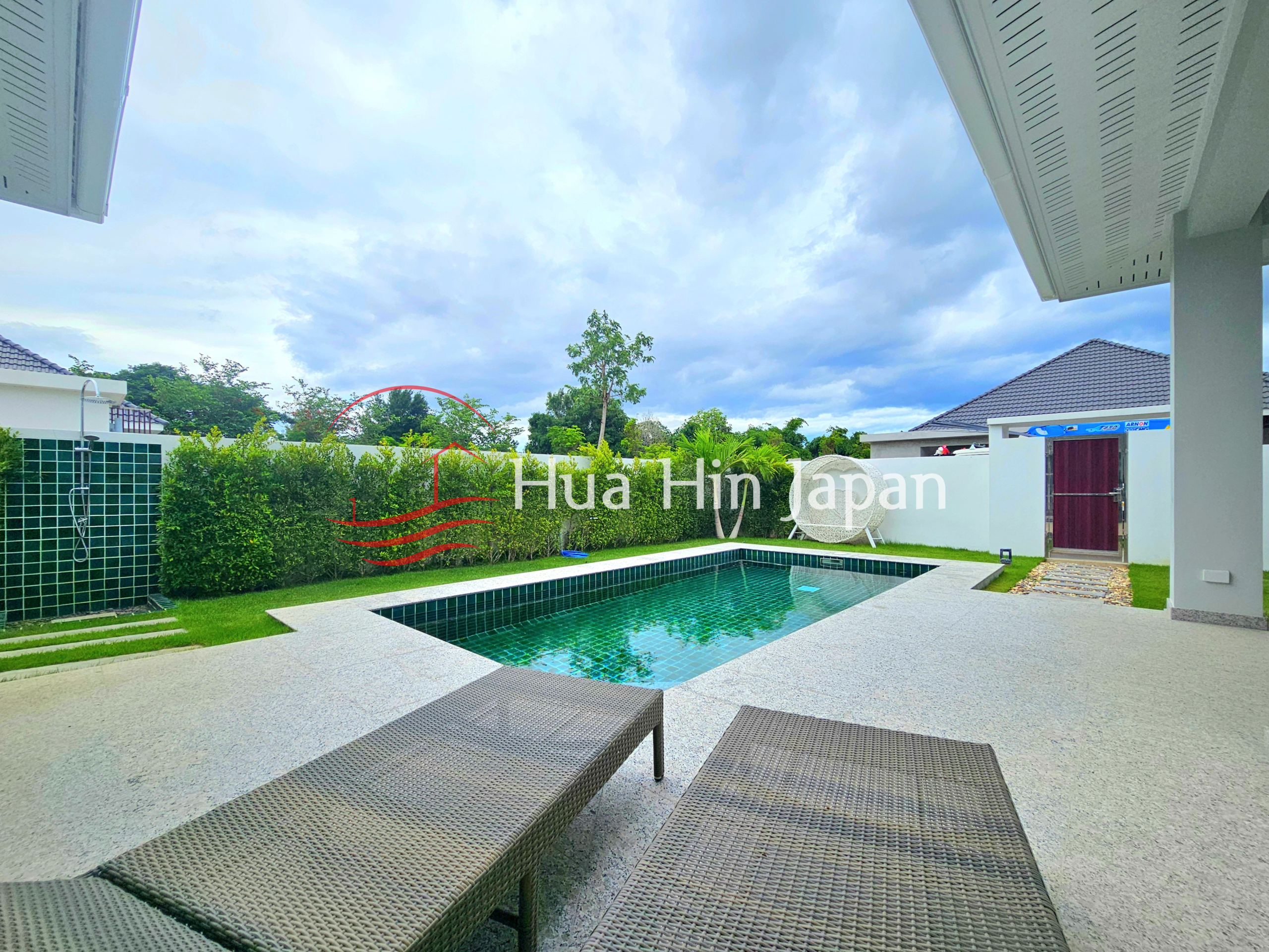 Private outdoor swimming pool surrounded by a landscaped garden, hedges, lounge chairs, and a paved pool deck