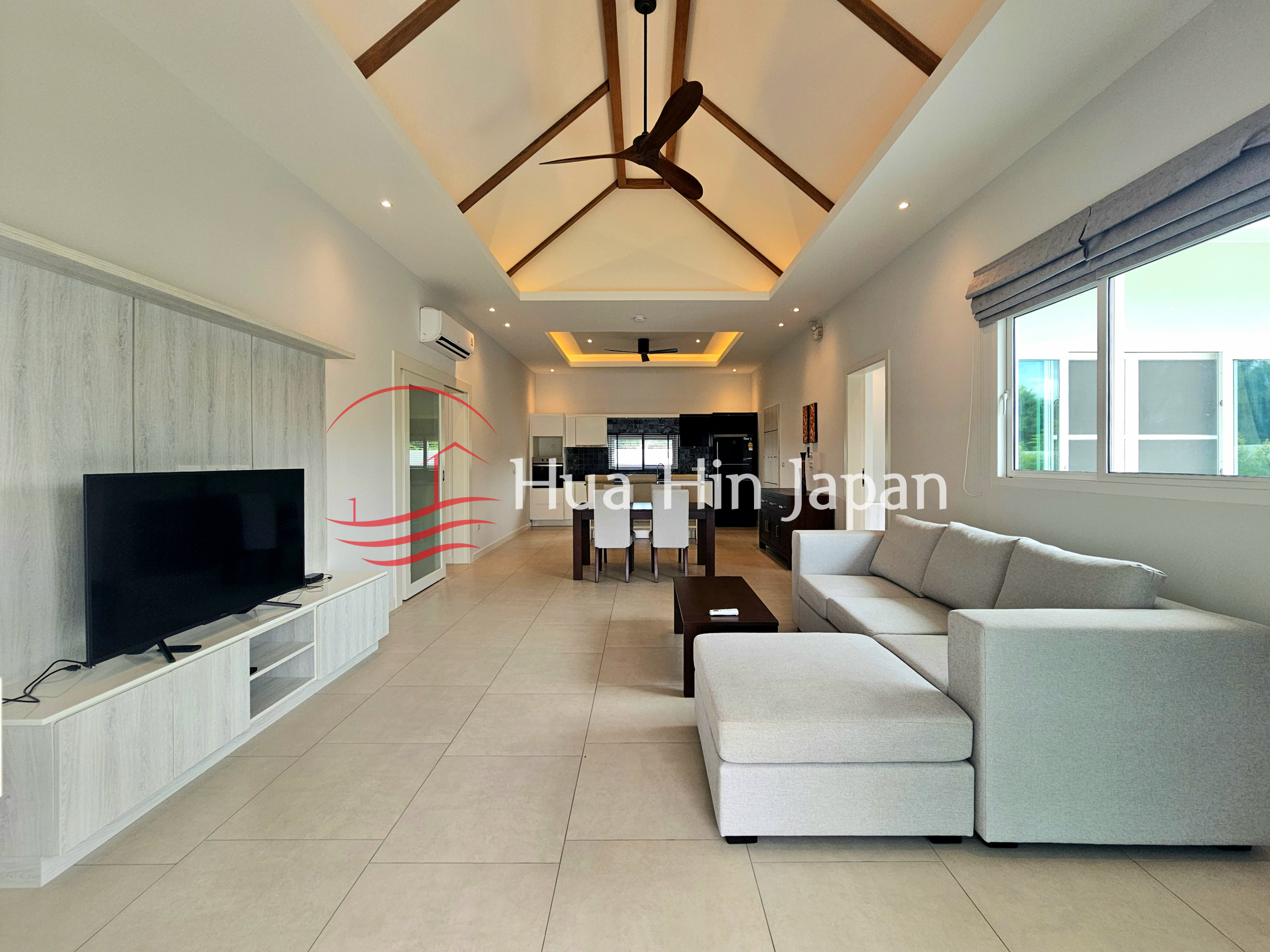 Spacious modern open-plan living room with sectional sofa, TV, dining area, and kitchen