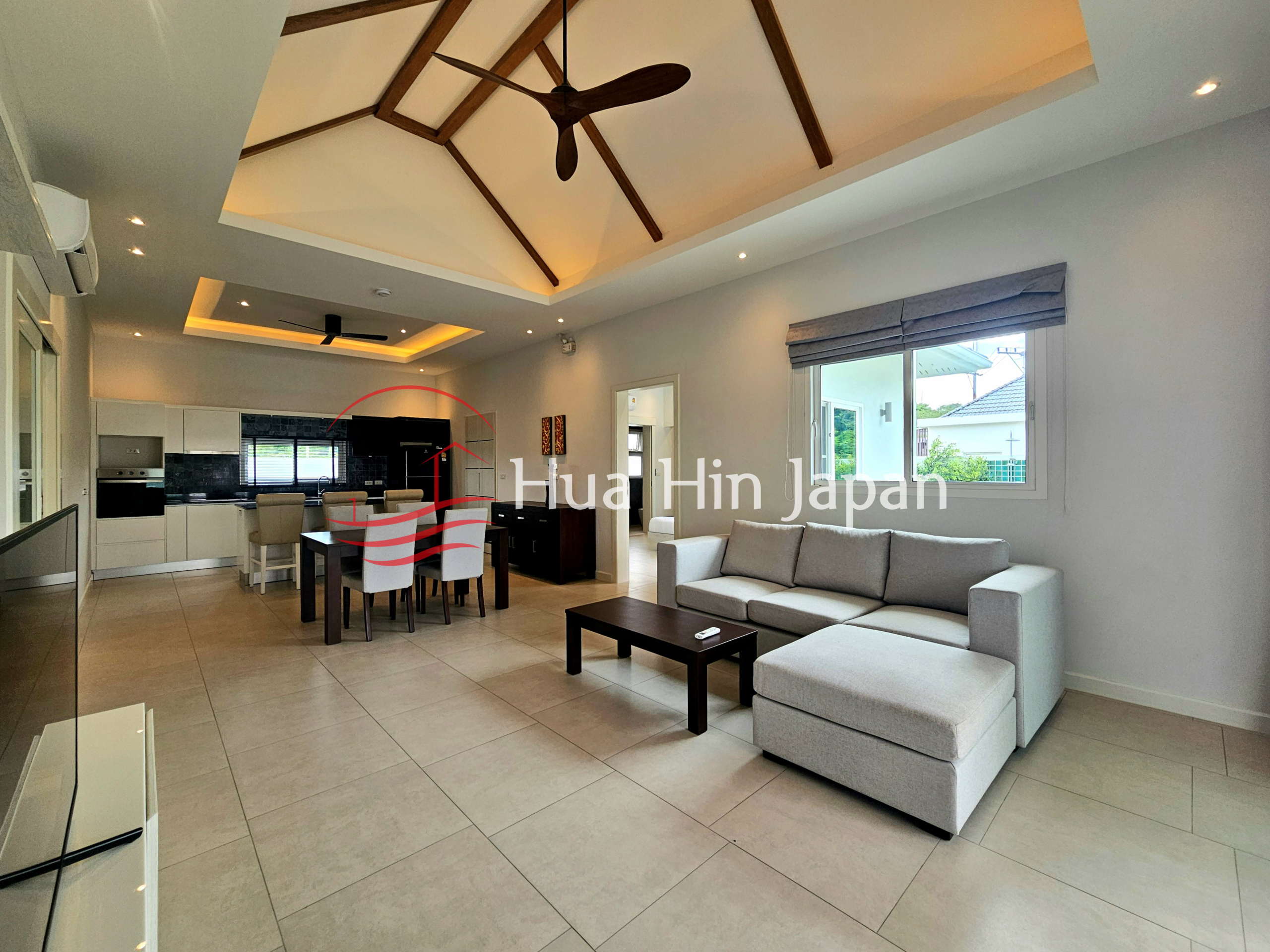 Spacious modern living room with sectional sofa, coffee table, dining area, and open kitchen
