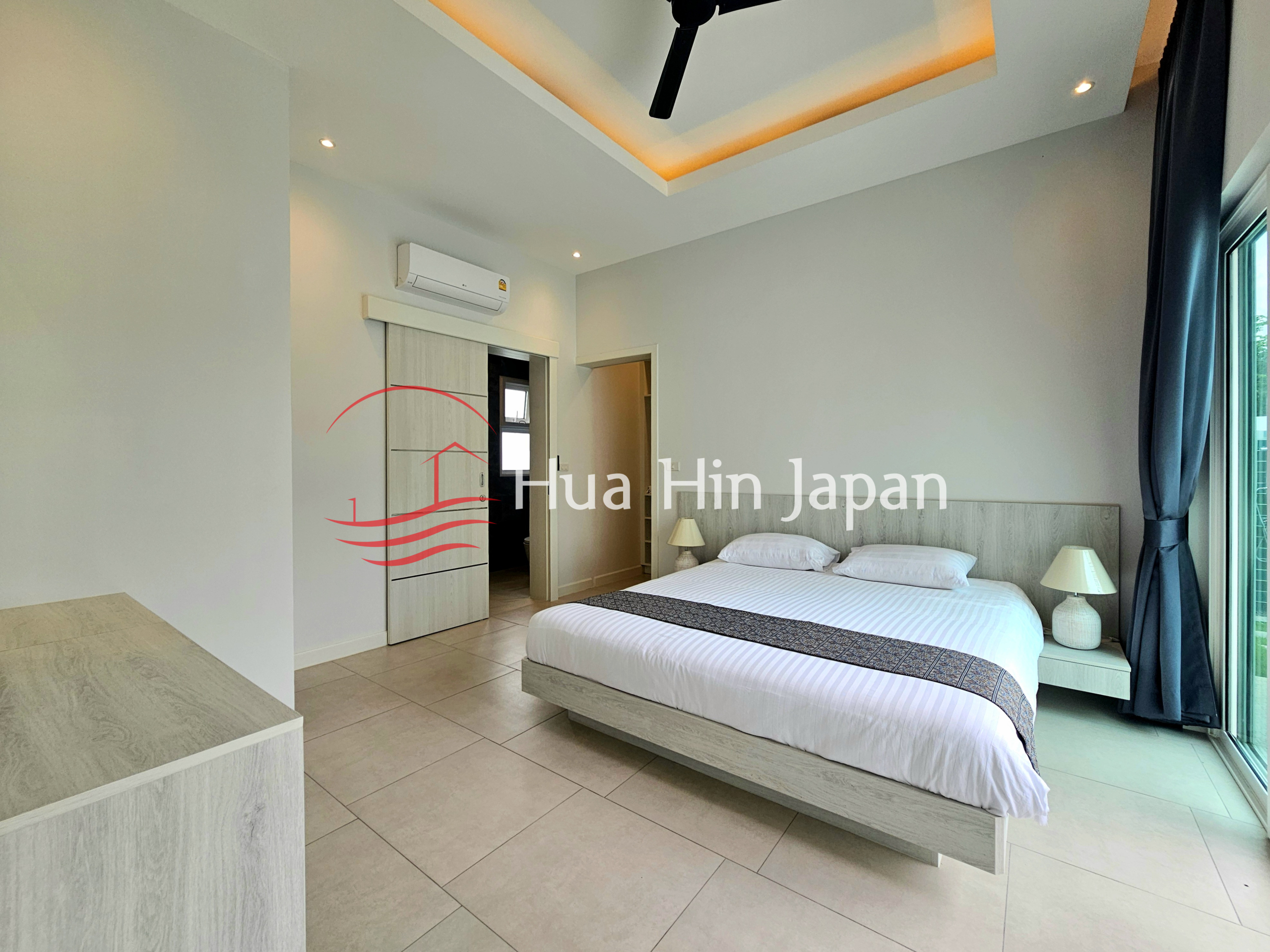 Modern bedroom with a king-size bed, wood-finish furniture, air conditioner, ceiling fan, and large glass doors