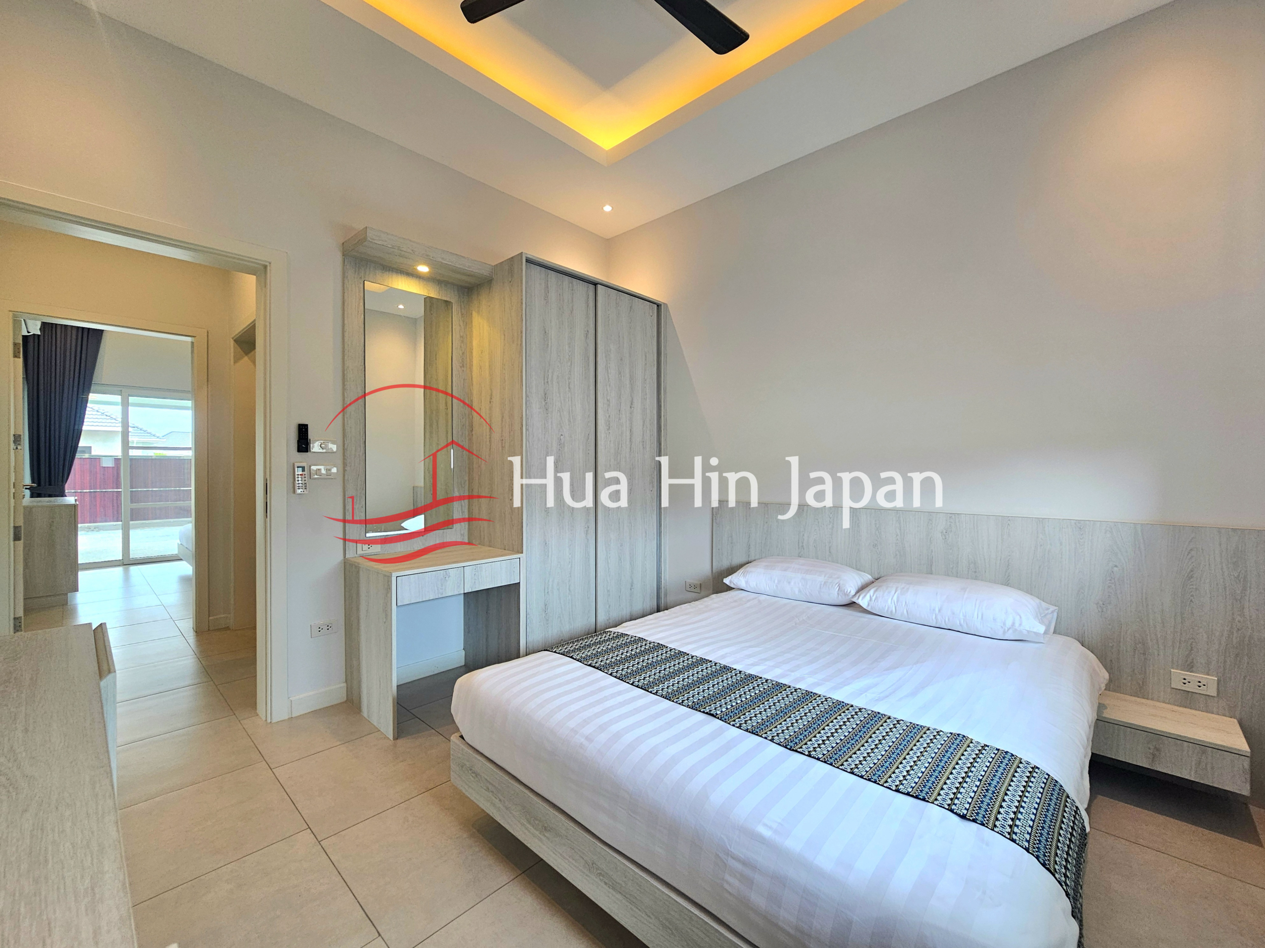 Modern bedroom with a king-size bed, built-in wardrobe, dressing table, and warm ceiling lighting
