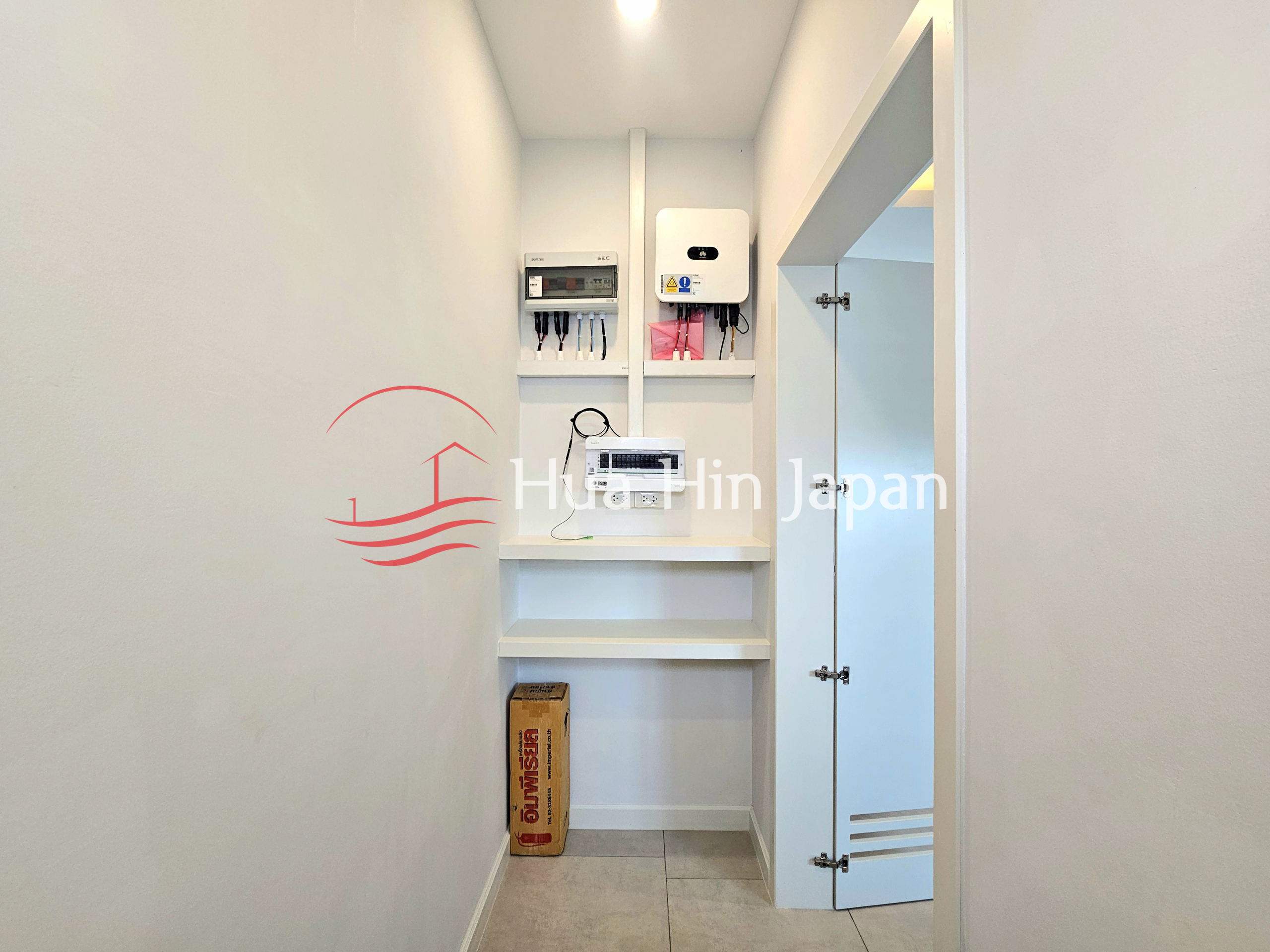 Compact utility room with electrical control panels, inverter system, shelving, and storage cabinet