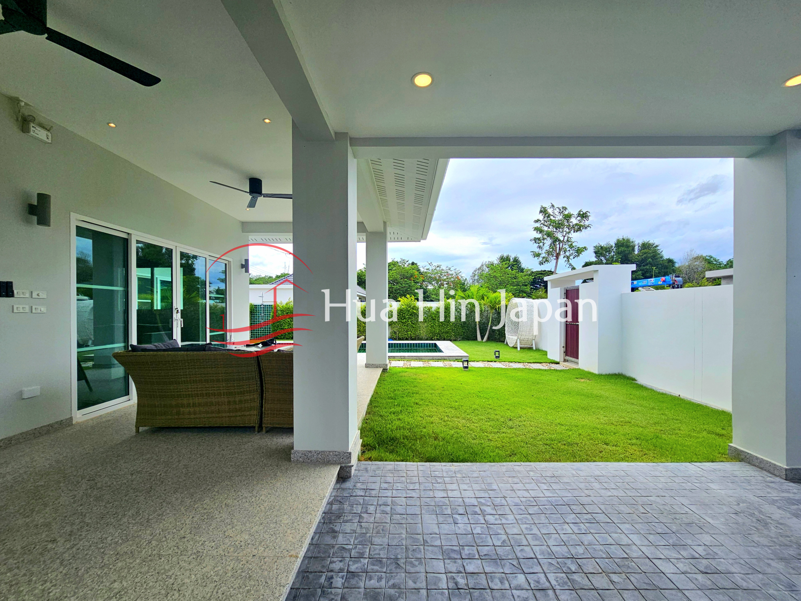 Covered outdoor patio overlooking a green lawn and swimming pool