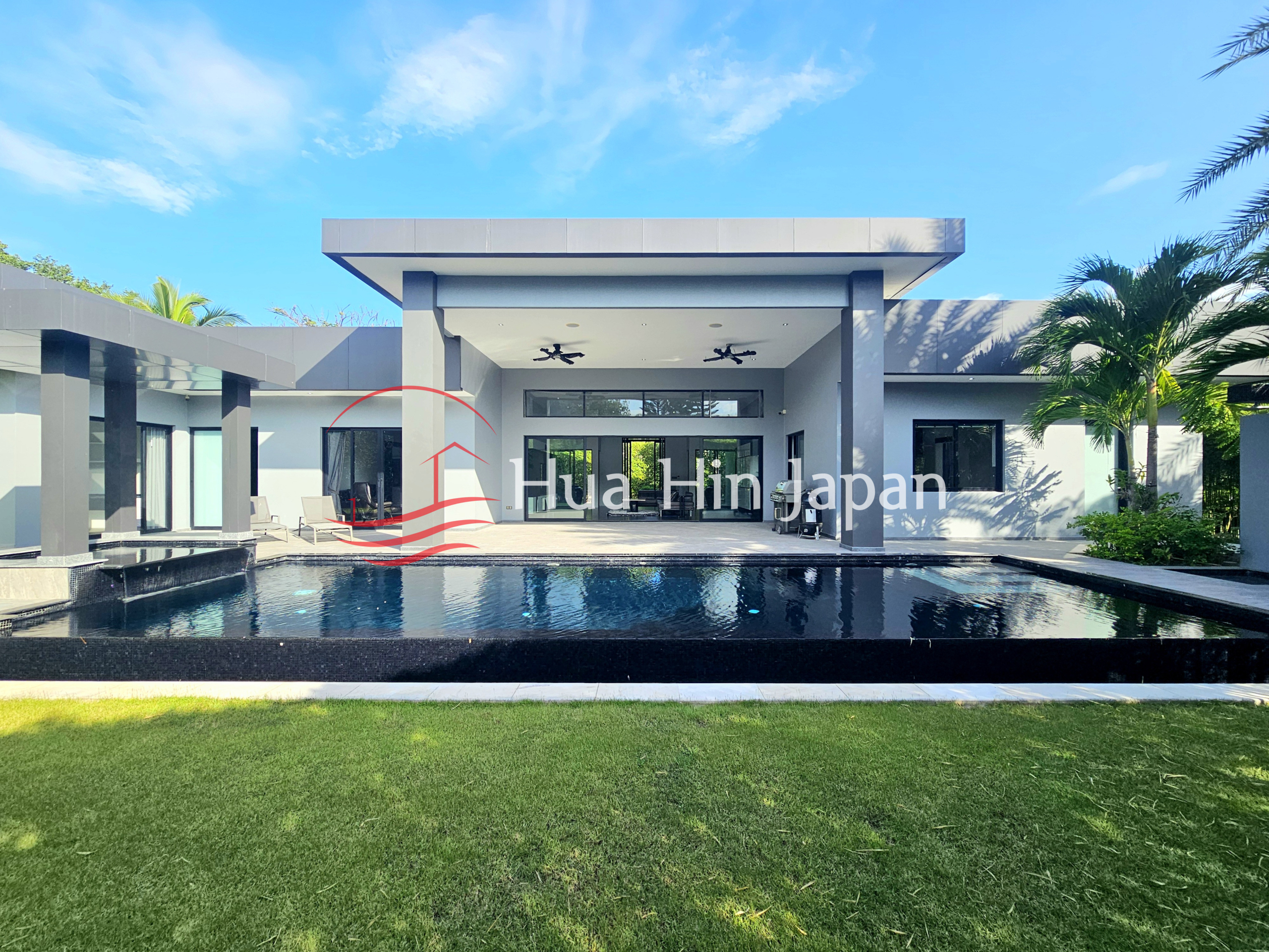 Modern luxury villa with a large private swimming pool, covered outdoor terrace, and tropical landscaping