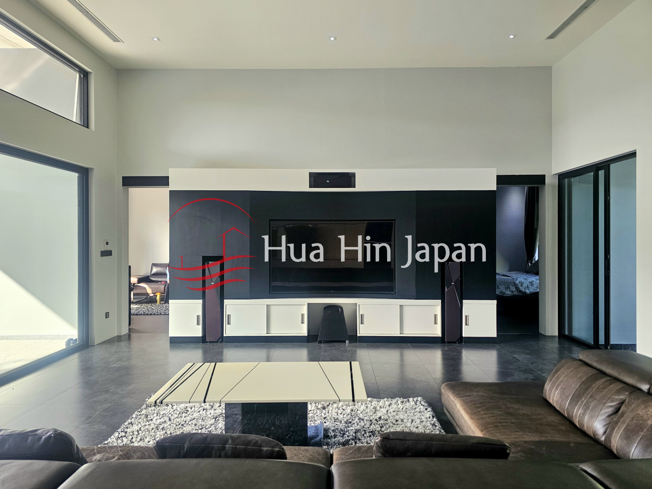 Modern living room with a large black and white TV wall, sectional sofas, and glass doors