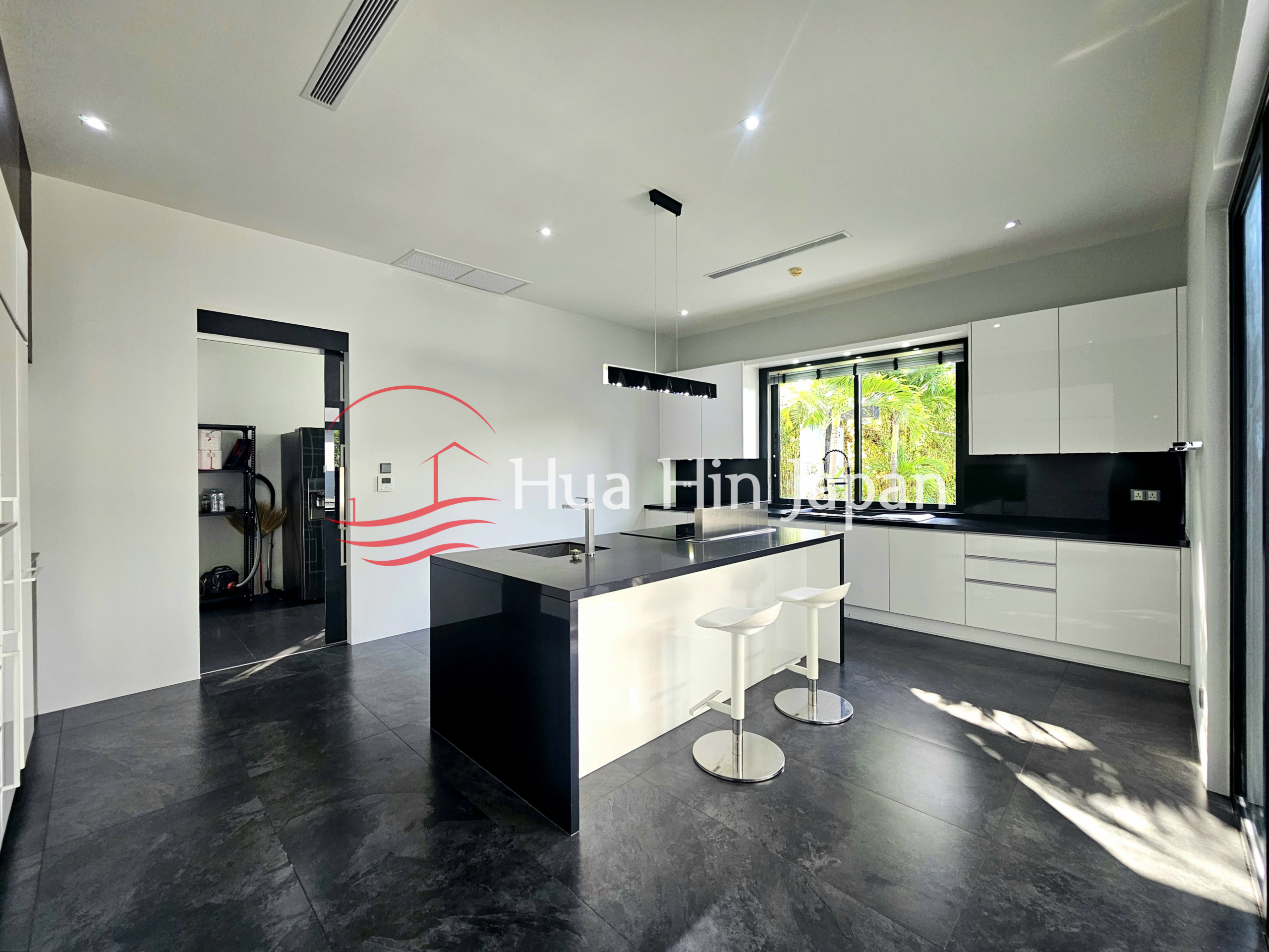 Modern black and white kitchen with a large central island, white cabinetry, and two bar stools