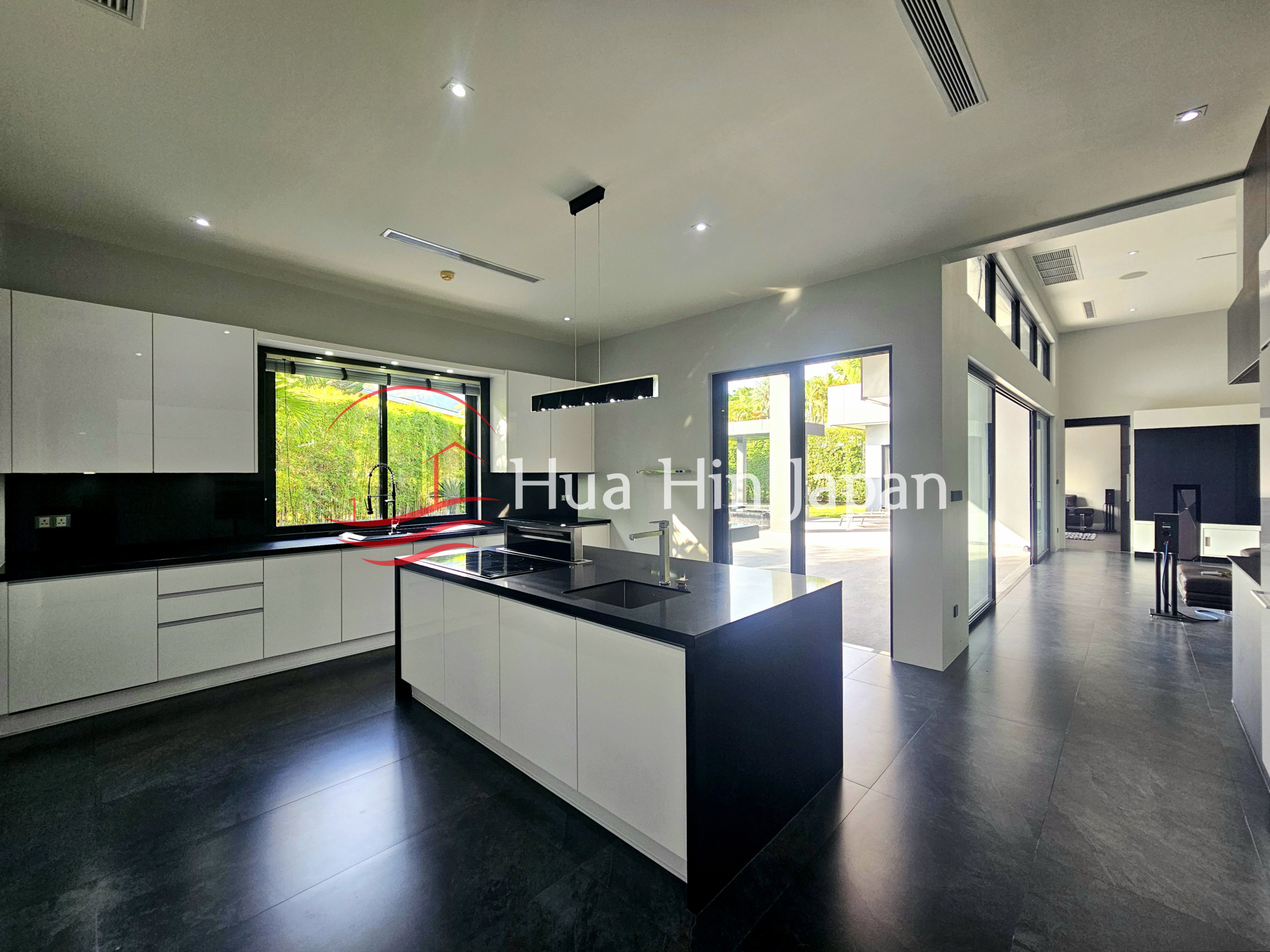 Modern open-plan kitchen with a large black and white island, sleek white cabinets, and glass doors