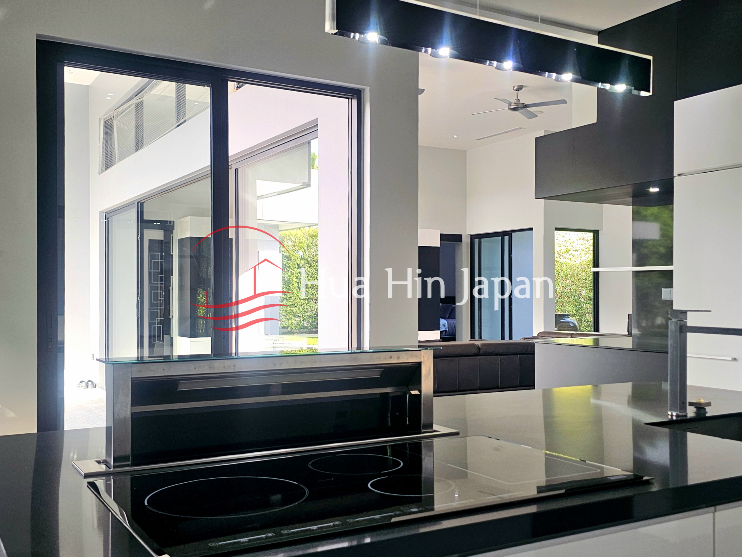 Modern open-plan kitchen with a black island, induction cooktop, and view into the living area