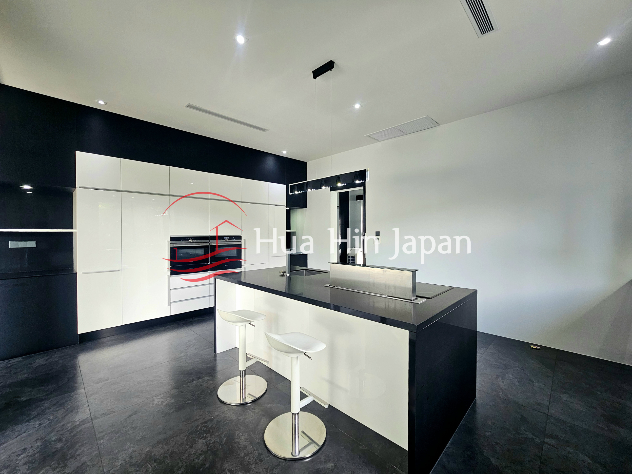 Modern black and white kitchen with a large central island and two bar stools