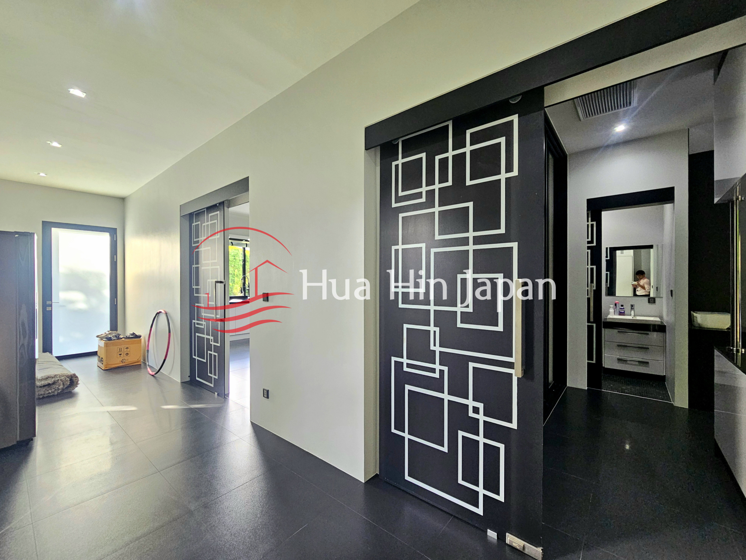 Modern hallway with black and white geometric sliding doors and glossy dark flooring