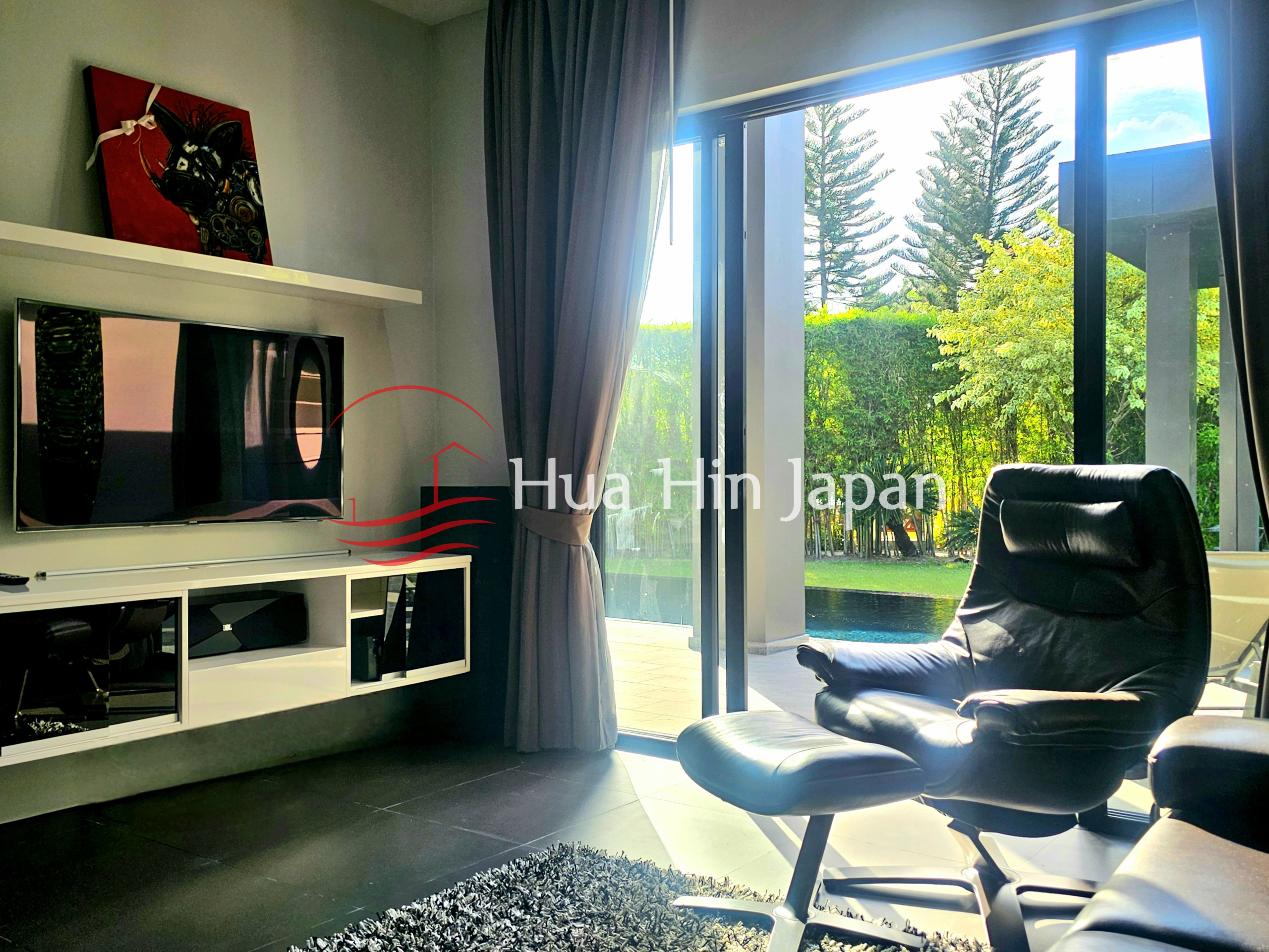 Modern living room with a TV, leather recliner, large glass doors, and pool view