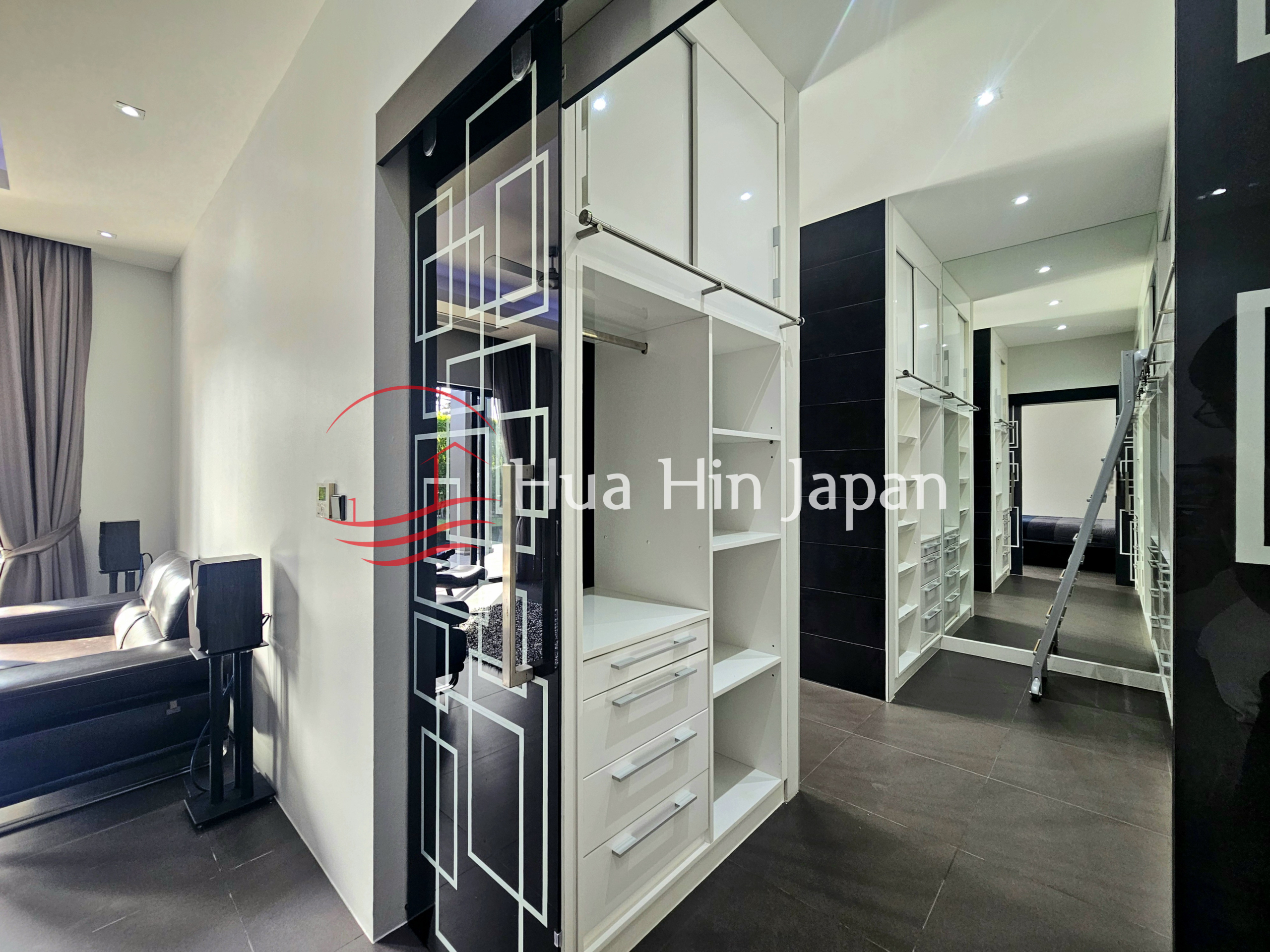 Modern walk-in wardrobe with white built-in storage cabinets, drawers, and mirrored doors