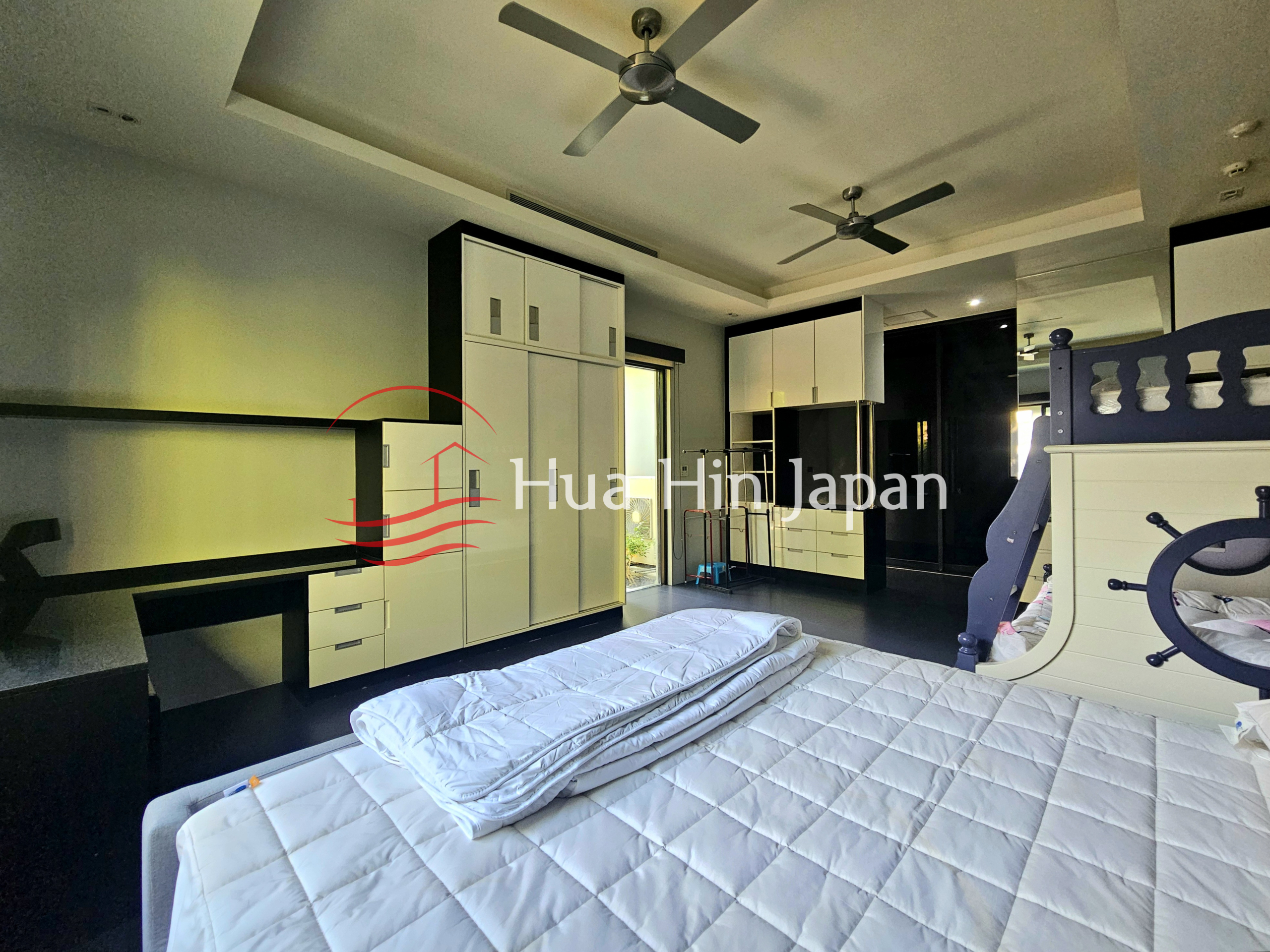 Spacious modern bedroom with bunk bed, built-in white wardrobes, black countertops, and ceiling fans