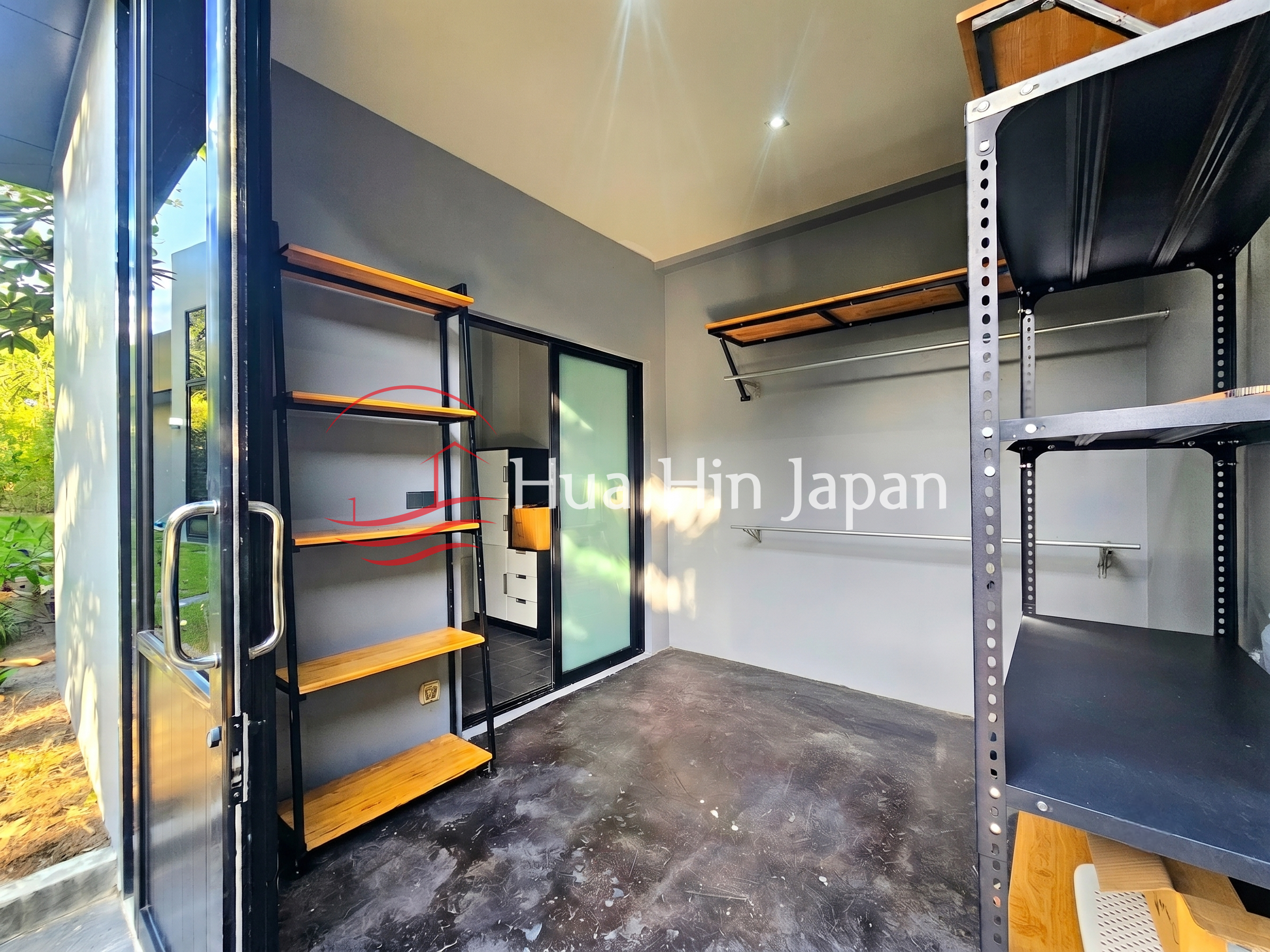 Modern private storage and utility room with wooden shelves, black metal shelving, and a workbench