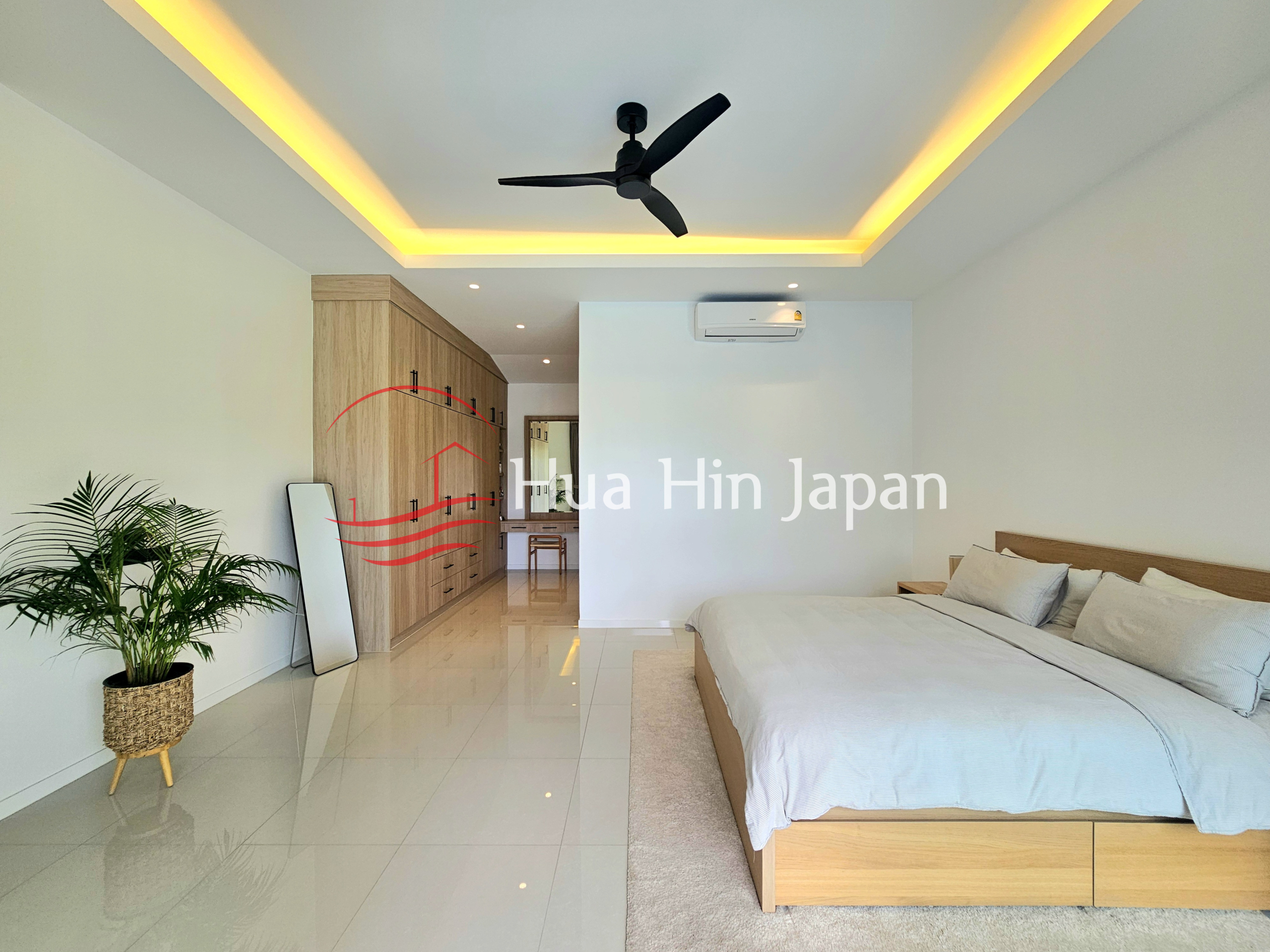 Spacious modern bedroom with a wooden bed, built-in wardrobe, ceiling fan, and warm recessed lighting