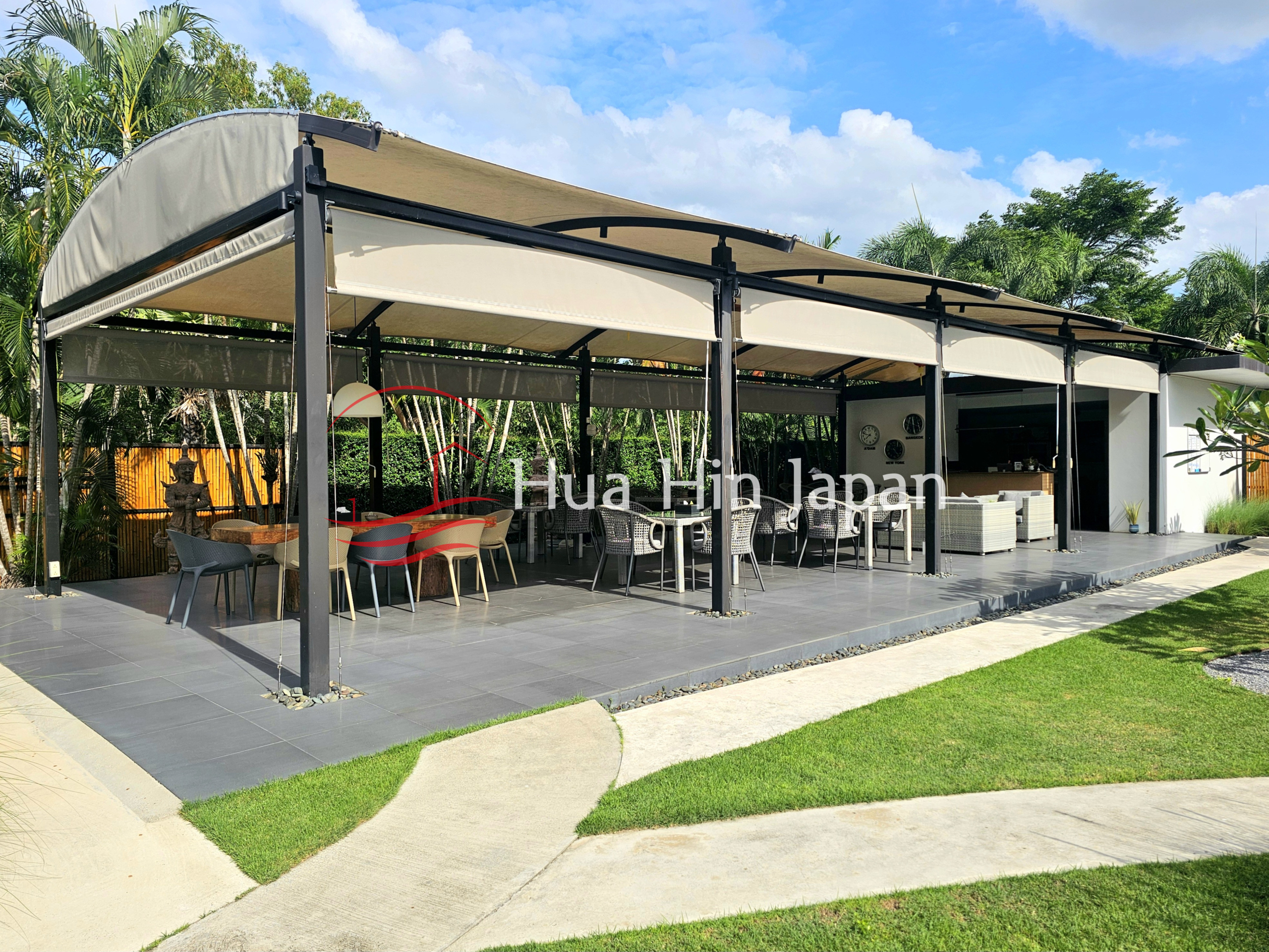 Spacious outdoor covered patio with dining tables, lounge seating, and a landscaped garden