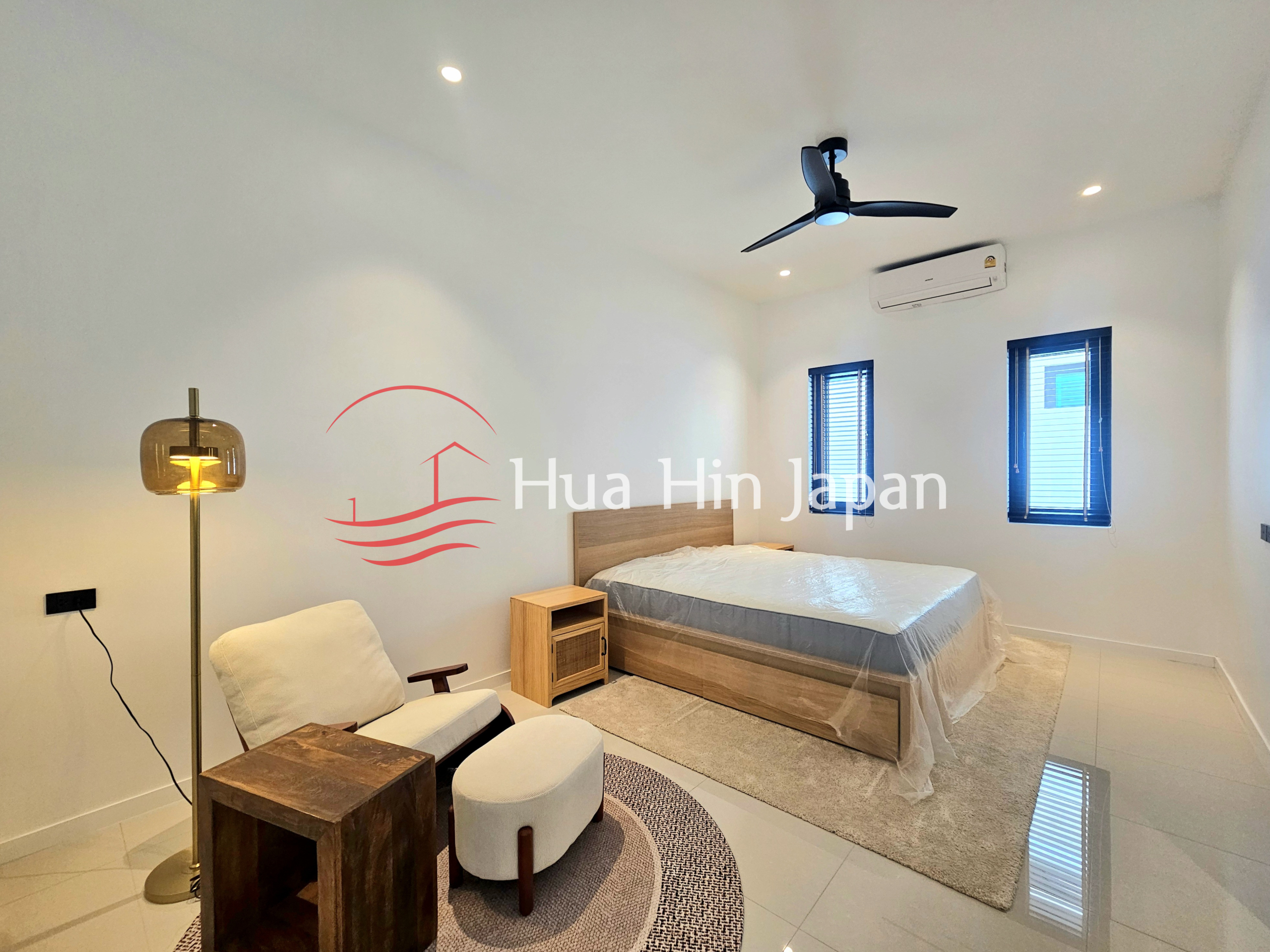 Spacious modern bedroom with a wooden bed, armchair, floor lamp, ceiling fan, and air conditioner