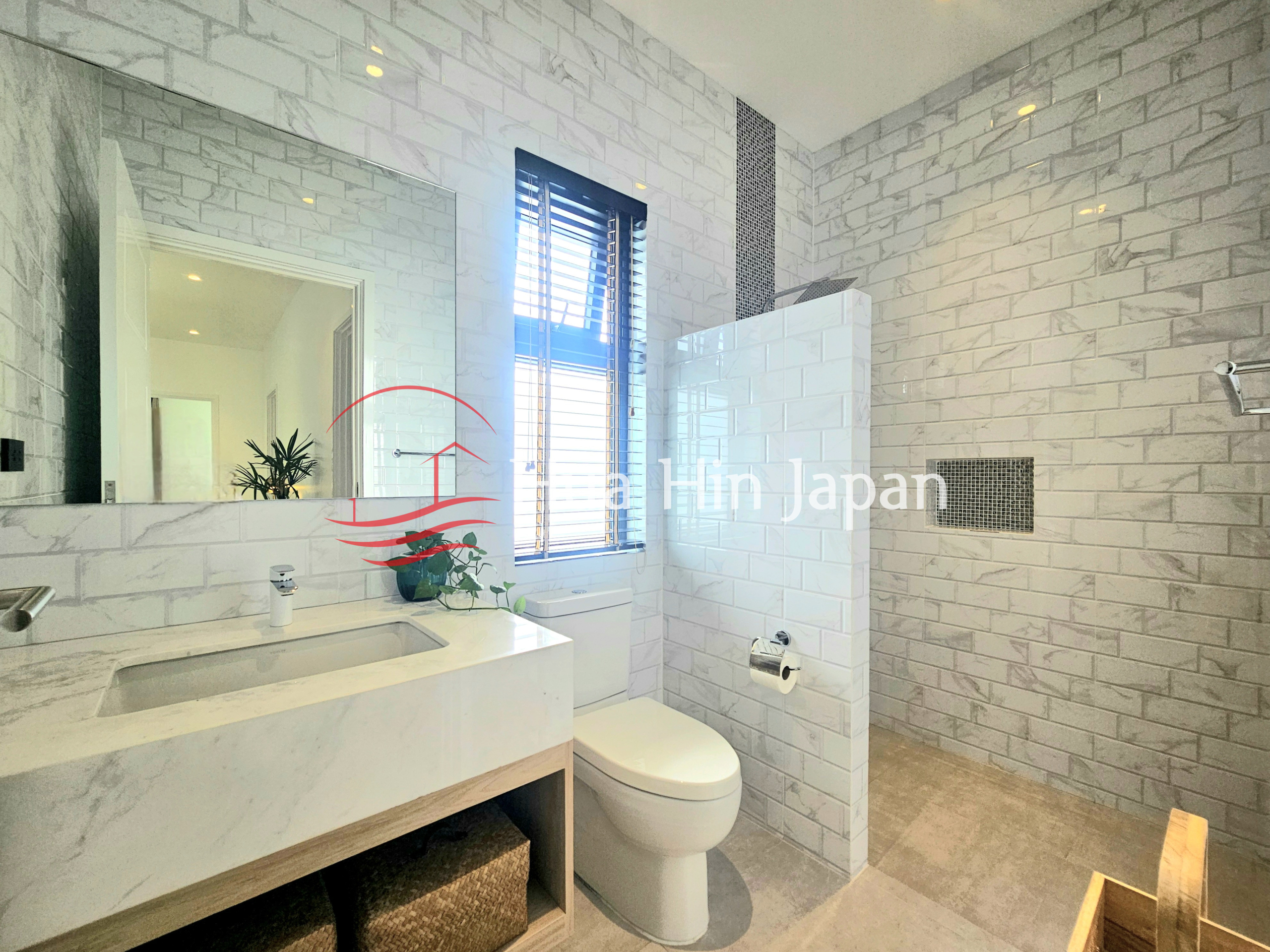 Modern bathroom with white brick-style tiles, floating vanity, toilet, large mirror, and spacious walk-in shower