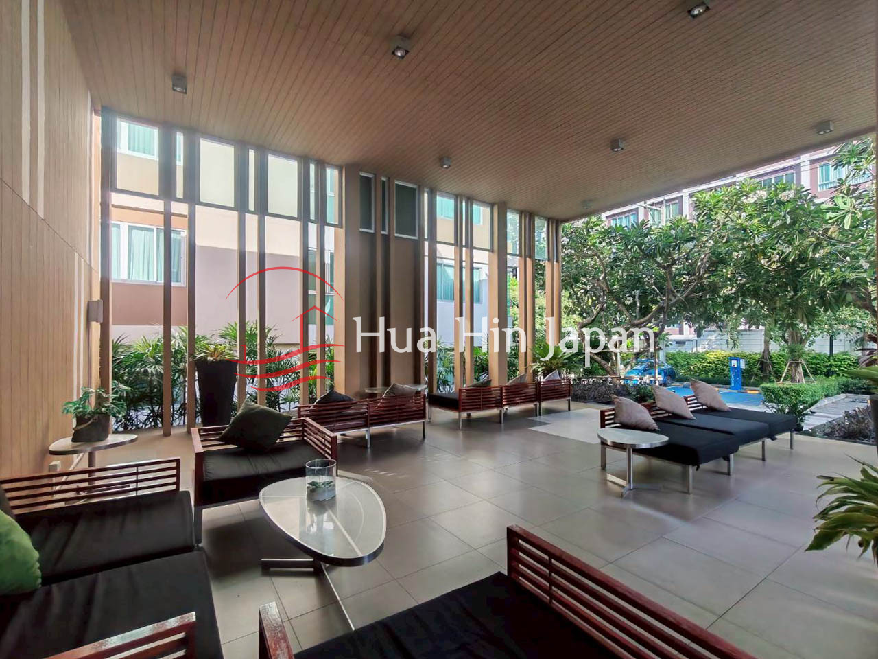 Modern resort lounge with comfortable seating, large glass windows, and tropical greenery