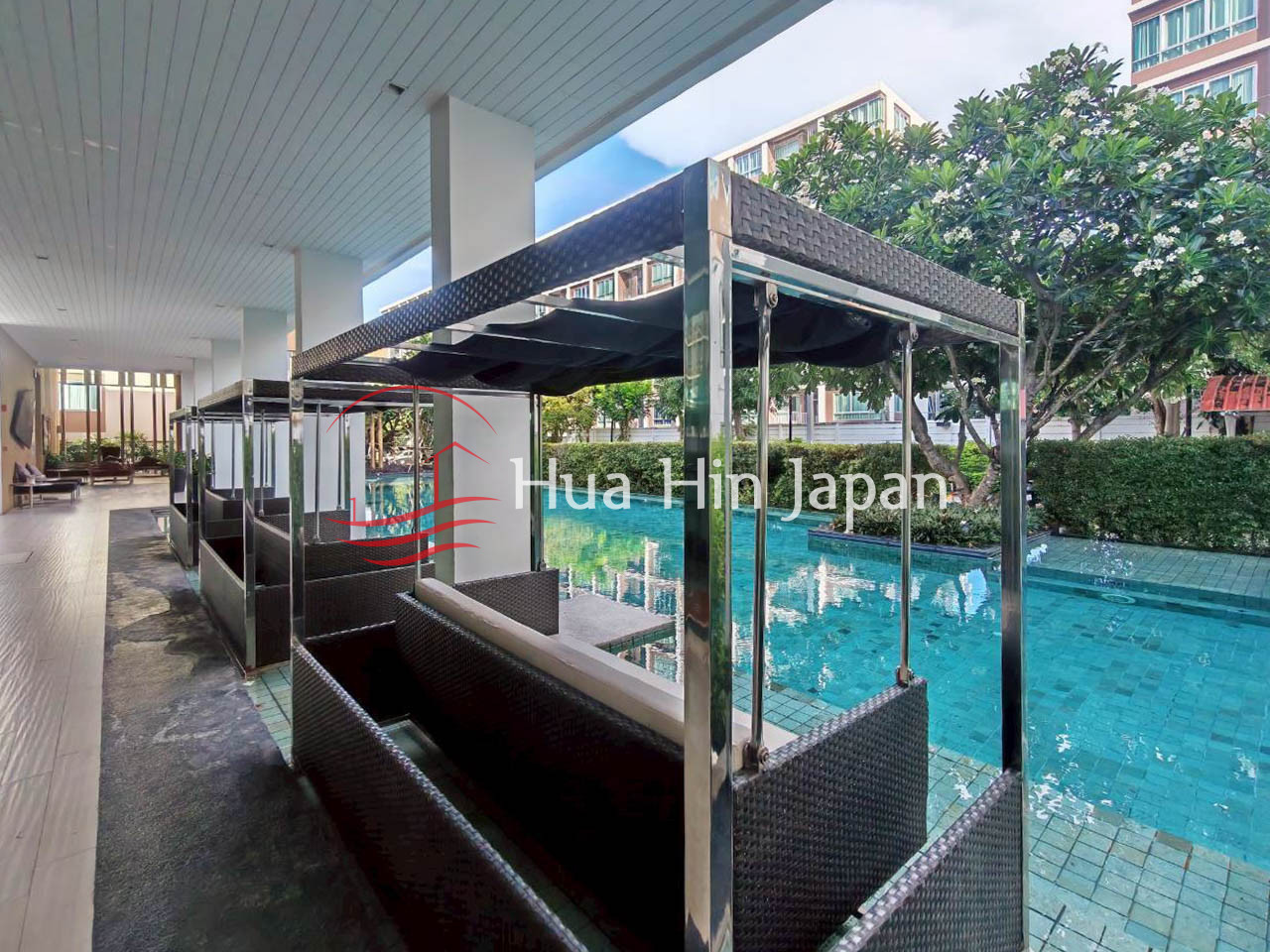 Resort swimming pool with covered outdoor seating and landscaped surroundings