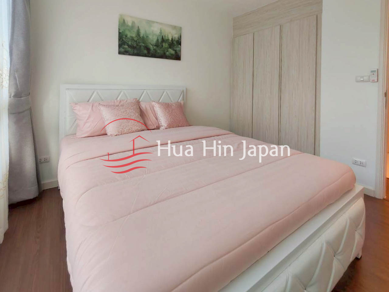 Cozy bedroom with a white upholstered bed, soft pink bedding, wooden wardrobe, and forest artwork