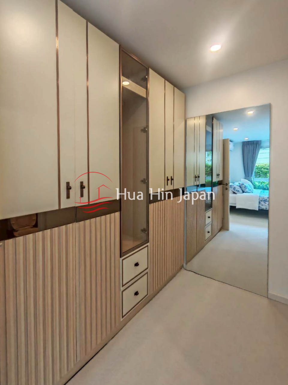 Built-in wardrobe with mirrored doors, drawers, and modern storage cabinets in a bedroom