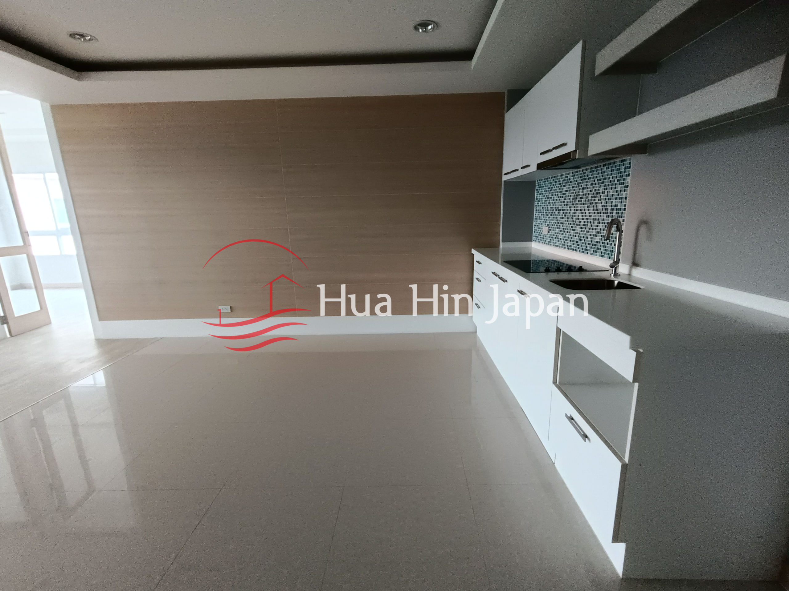 Modern open-plan interior with a built-in kitchen, white cabinets, and mosaic backsplash