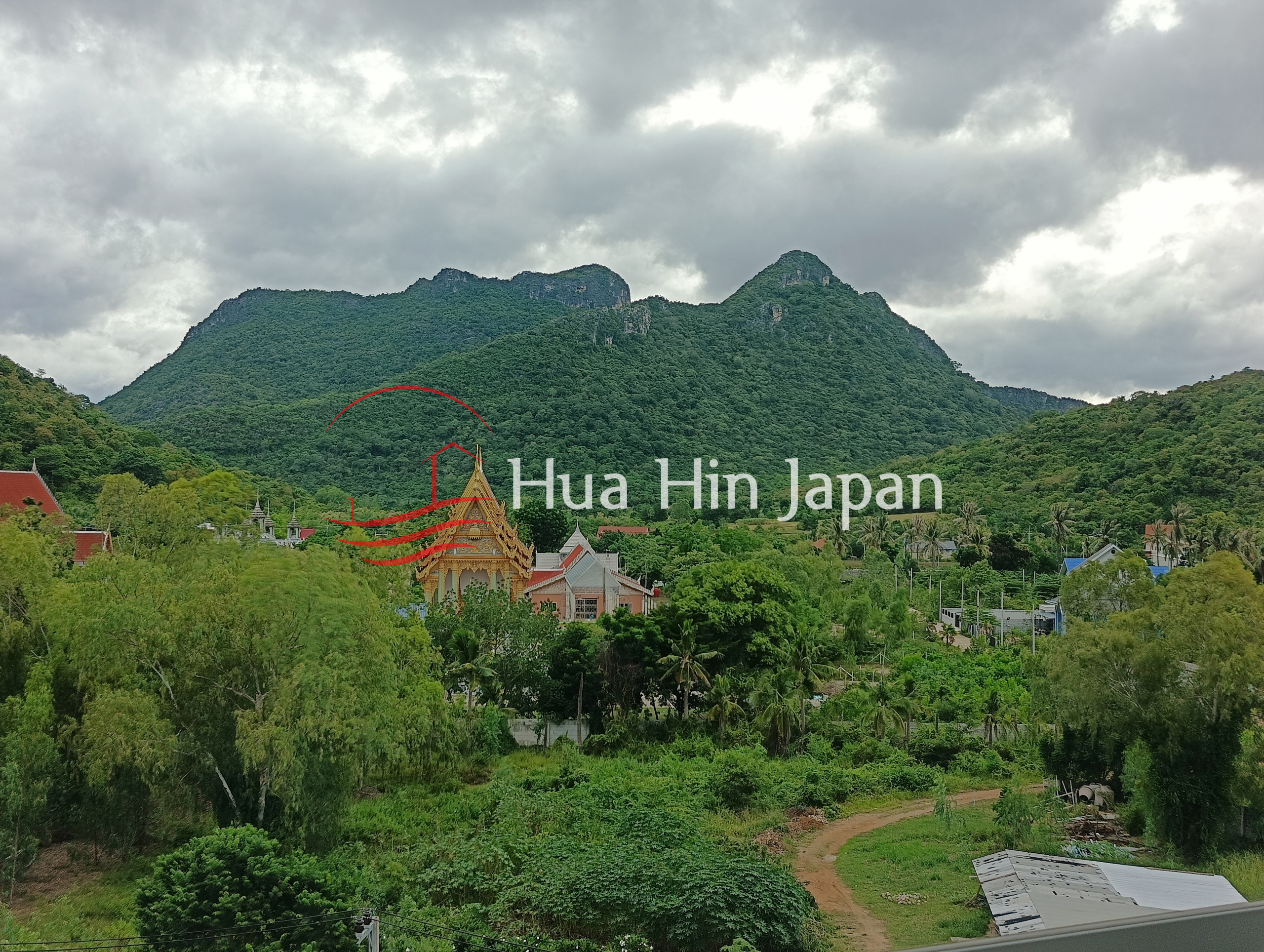 Lush green mountain landscape with a traditional Thai temple and tropical vegetation
