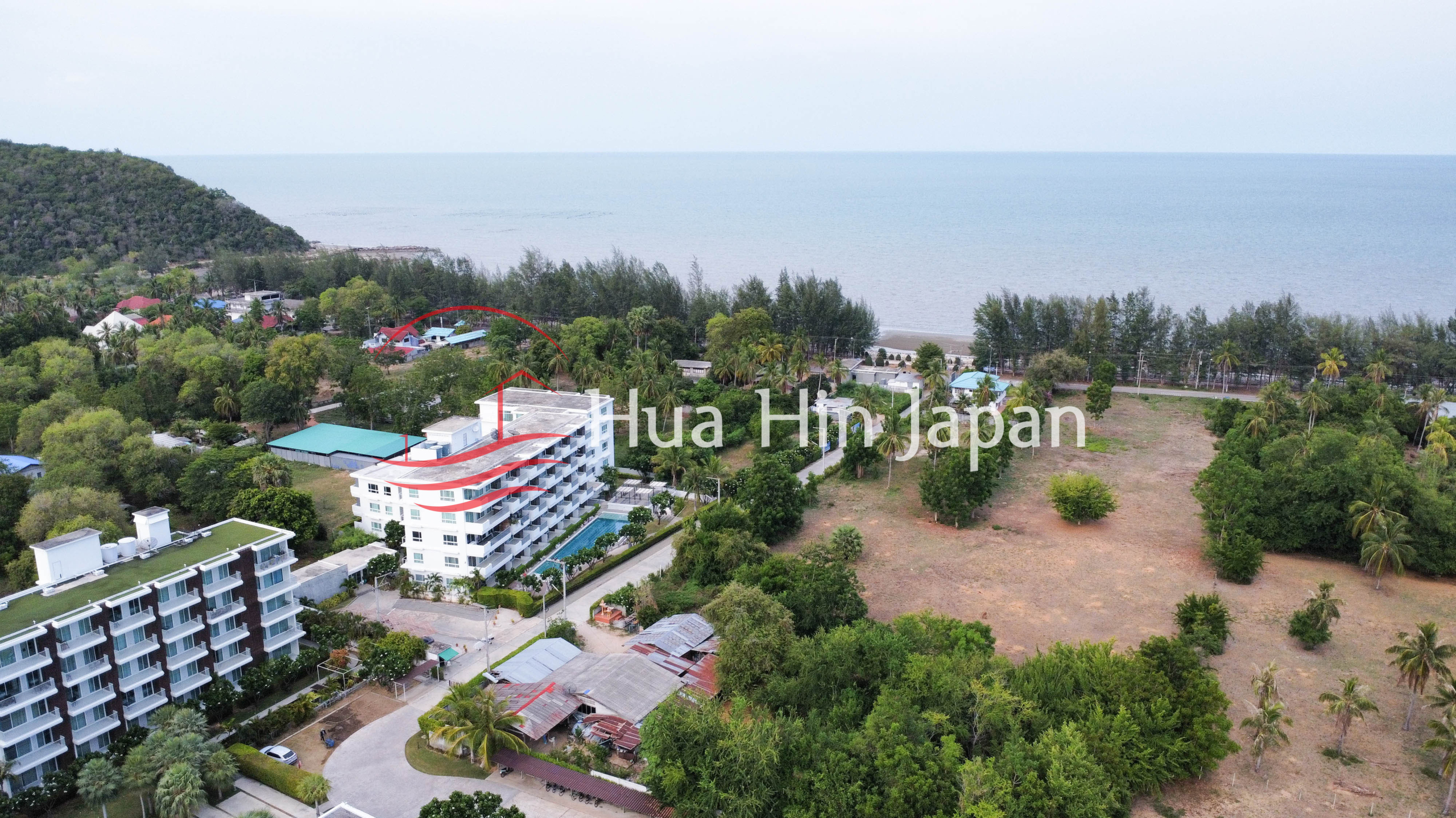 Aerial view of a beachfront condominium surrounded by tropical greenery and coastal landscape